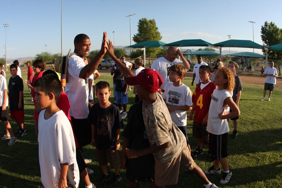 MARINE CORPS AIR GROUND COMBAT CENTER TWENTYNINE PALMS, Calif. – Chris Hayes, former safety for the Green Bay Packers and Super Bowl XXXI champion, gives a high-five to 10-year-old Bayani Rose during a youth sports-sponsored football camp at Felix Field July 15.