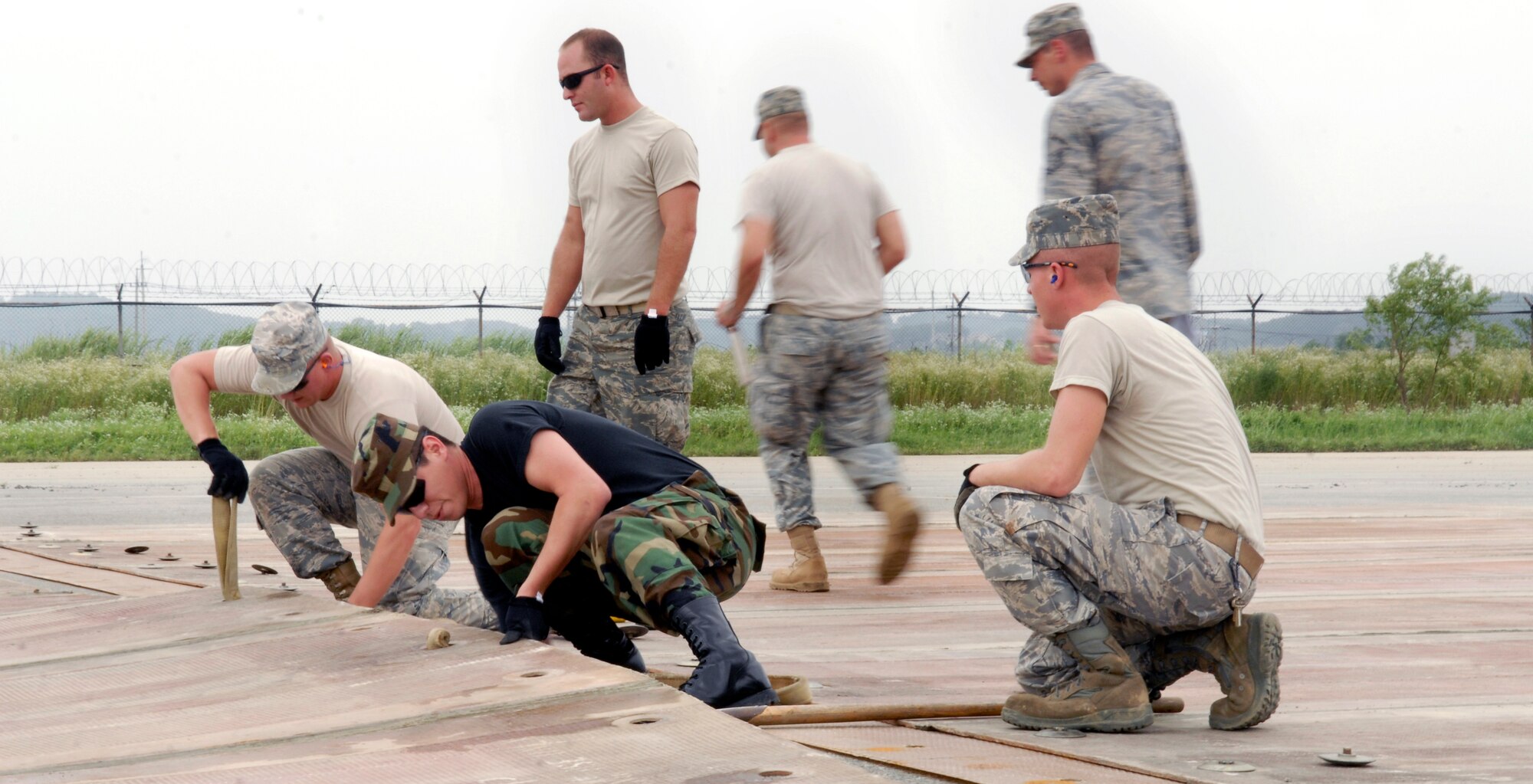 Airmen from the 51st Civil Engineering Squadron guide a folded fiberglass mat into place during airfield damage repair training at Osan Air Base, Republic of Korea, July 15.  The 30x54 foot mats are used to quickly repair runway damage, and can be connected to cover a large areas. (U.S. Air Force photo/Senior Airman Stephenie Wade)
