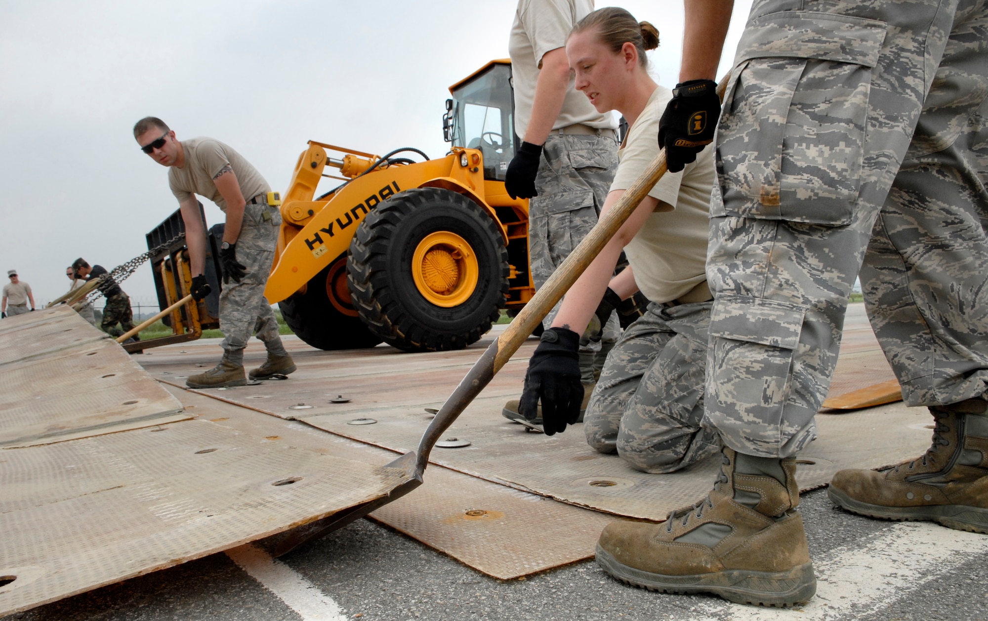 Airmen from the 51st Civil Engineering Squadron guide a folded fiberglass mat into place during airfield damage repair training at Osan Air Base, Republic of Korea, July 15.  The 30x54 foot mats are used to quickly repair runway damage, and can be connected to cover a large areas. (U.S. Air Force photo/Staff Sgt. Brian Ferguson)
