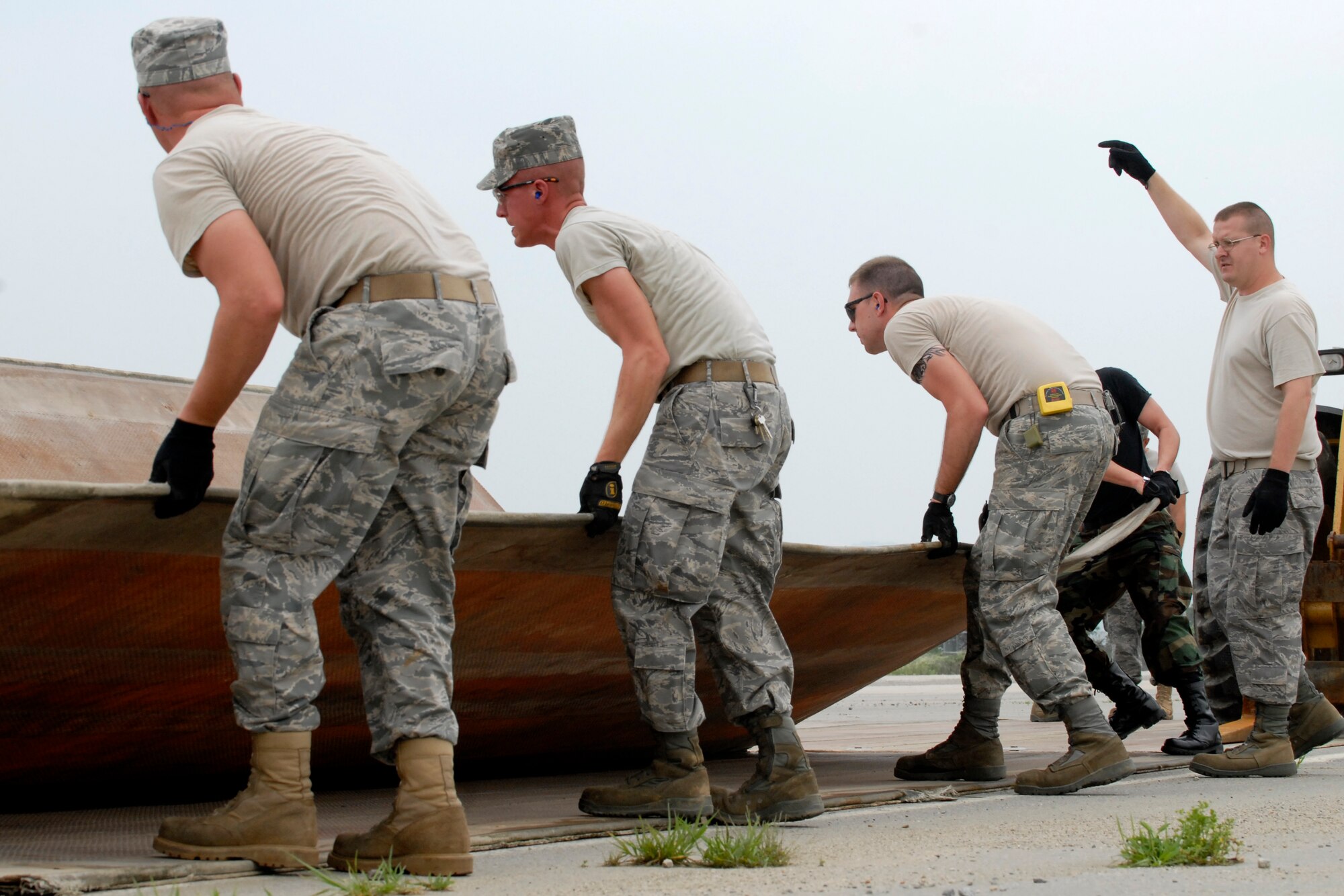 Airmen from the 51st Civil Engineering Squadron unfold a folded fiberglass mat  during airfield damage repair training at Osan Air Base, Republic of Korea, July 15.  The 30x54 foot mats are used to quickly repair runway damage, and can be connected to cover a large areas. (U.S. Air Force photo/Staff Sgt. Brian Ferguson)

