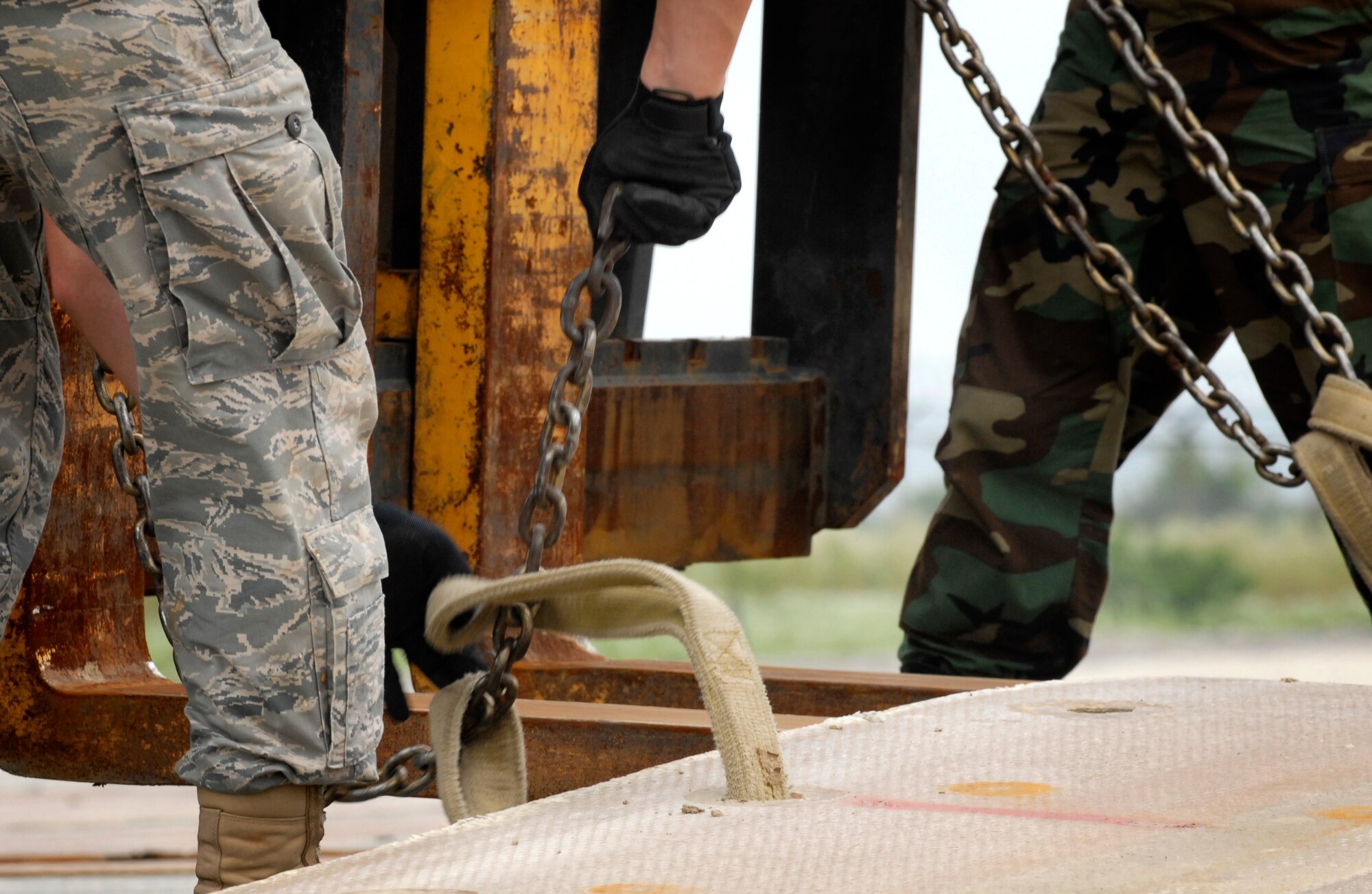 Airmen from the 51st Civil Engineering Squadron connect chains to a folded fiberglass mat and fork-lift during airfield damage repair training at Osan Air Base, Republic of Korea, July 15.  The 30x54 foot mats are used to quickly repair runway damage, and can be connected to cover a large areas. (U.S. Air Force photo/Staff Sgt. Brian Ferguson)

