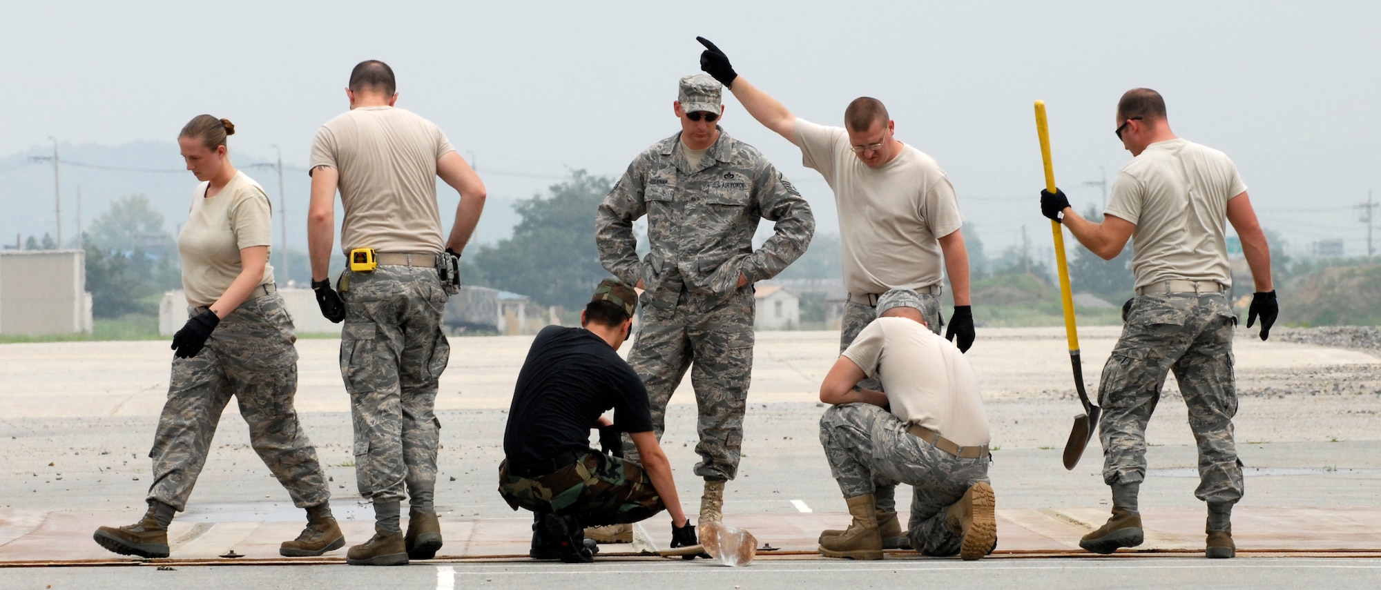 Airmen from the 51st Civil Engineering Squadron guide a folded fiberglass mat into place during airfield damage repair training at Osan Air Base, Republic of Korea, July 15.  The 30x54 foot mats are used to quickly repair runway damage, and can be connected to cover a large areas. (U.S. Air Force photo/Staff Sgt. Brian Ferguson)
