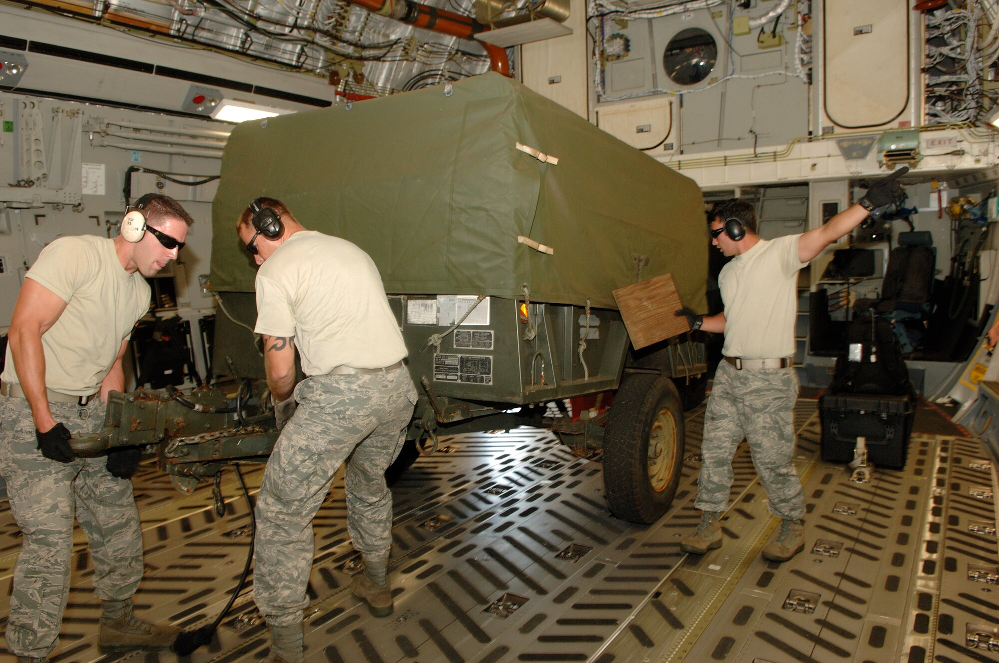HICKAM AIR FORCE BASE, Hawaii -- Pacific Mobility Warriors position a humvee trailer for tie-down on a C-17 July 14 during an Engines Running Onload/Offload event in preparation for the 2009 Air Mobility Rodeo July 18-24 at McChord Air Force Base, Wash. Team members from left to right are Staff Sgt. Cliff Robertson, 735th Air Mobility Squadron, Hickam AFB; Staff Sgt. Travis Wilt, 733rd Air Mobility Squadron,  Kadena Air Base, Japan; and Staff Sgt. Dustin Barboza, 734th Air Mobility Squadron, Andersen AFB, Guam. A team of eight air transportation specialists from around the Pacific are training together at Hickam AFB prior to the Rodeo. The team will compete against 22 other aerial port teams. Events include C-130 engine running on and off load, joint inspection with hazmat, in-transit visibility, 60,000-ton driving course, and a 10,000-ton forklift driving course. (U.S. Air Force photo/Mark Bates)