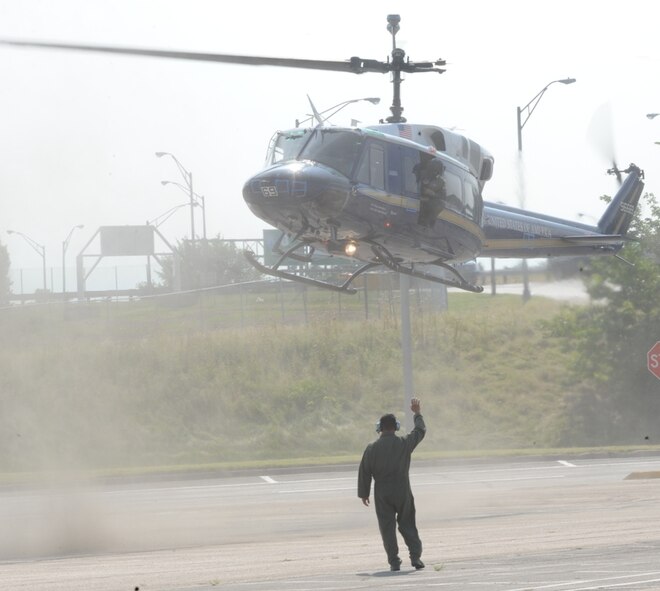 Capt. Daniel Ramirez of the 1st Helicopter Squadron flags a clean 1 HS aircraft into a vacant Pentagon parking lot coated in bio-agent simulant. The clean helo and its pilots, members of the 316th Wing at Andrews AFB, M were later swabbed to measure how contaminated they became as a result of the rotor wash. The airmen were part of 18 different state and federal agencies assisting the Pentagon Force Protection Agency in an Operational Response Test that took place July 11 on the Pentagon Reservation. The test was designed to provide first responders with information on the best methods to decontaminate people following a biological attack.