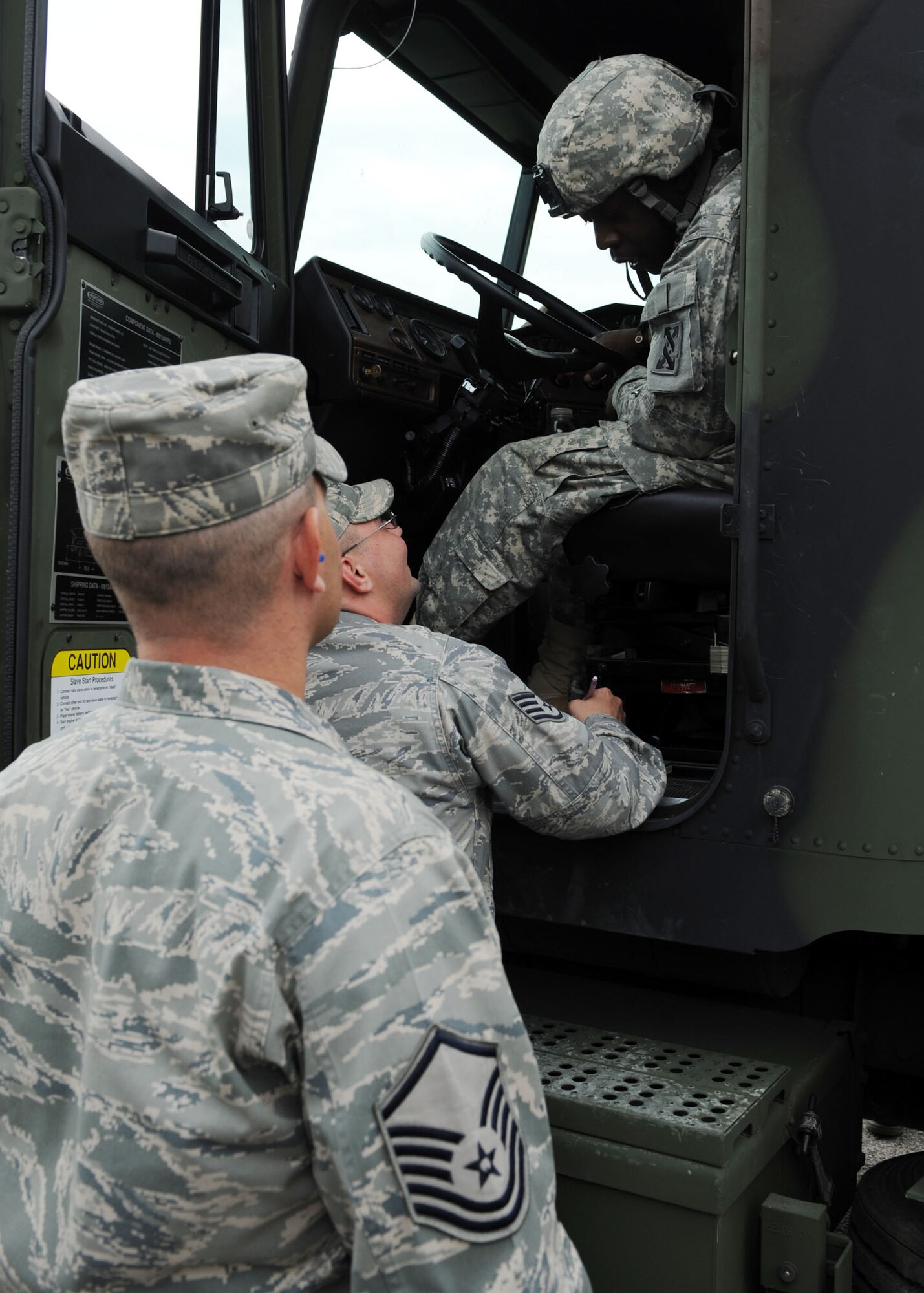 SCOTT AIR FORCE BASE, Ill. -- Master Sgt. Jim Landis, 375th Logistics Readiness Squadron fuels operations superintendent, and Tech. Sgt. Chris Guleff 375th Logistics Readiness Squadron refueling maintenance, talk with truck drive Spc. Sean Roberts, 206th Army Reserve Unit, while waiting for his truck to get fueled up on Scott, July 14. Specialist Roberts is driving one of many trucks taking part in Operation Golden Cargo.(U.S. Air Force photo/ Airman 1st Class Wesley Farnsworth)