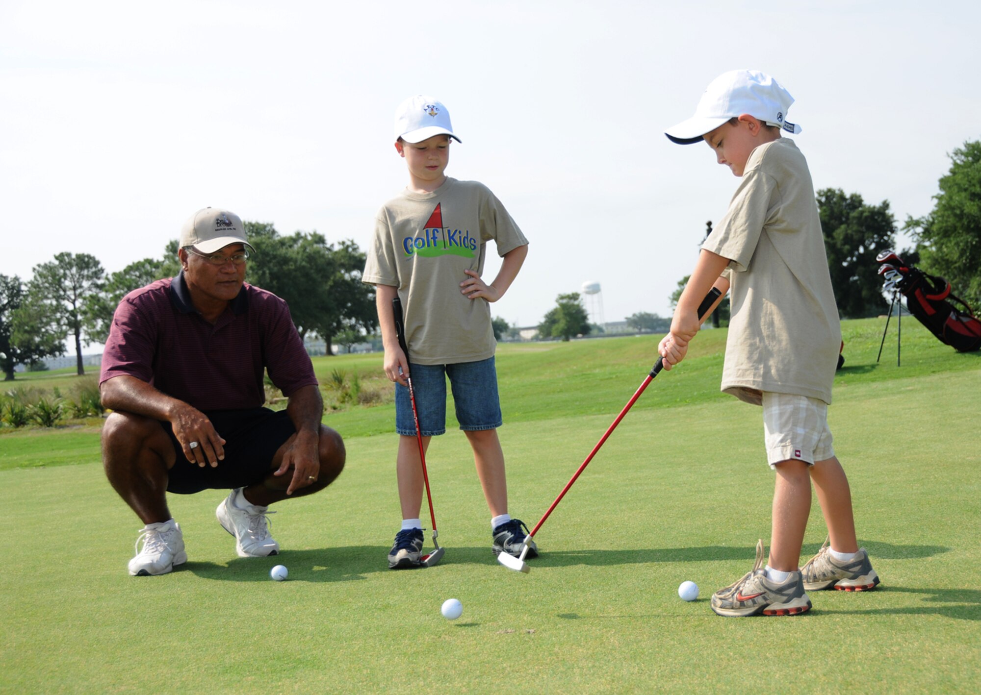 Bay Breeze Golf Course golf pro Tama Manu gives some putting pointers to 8-year-old Addison Robbins, center, and 6-year-old Trey Pickich during the first kids’ golf camp session, July 8.  Addison’s parents are Laurie and Jeffrey Robbins, 335th Training Squadron.  Trey, grandson of retiree Dan Russell, is the son of Kristen and Chad Pickich.  The second session began Tuesday and ends today, and the third session is July 28-30.  Ages 6-8 have lessons from 8:30-9:30, and ages 9-12 have lessons from 9:30-11:30 a.m.  Sign up at the youth center or Bay Breeze.  (U.S. Air Force photo by Kemberly Groue)