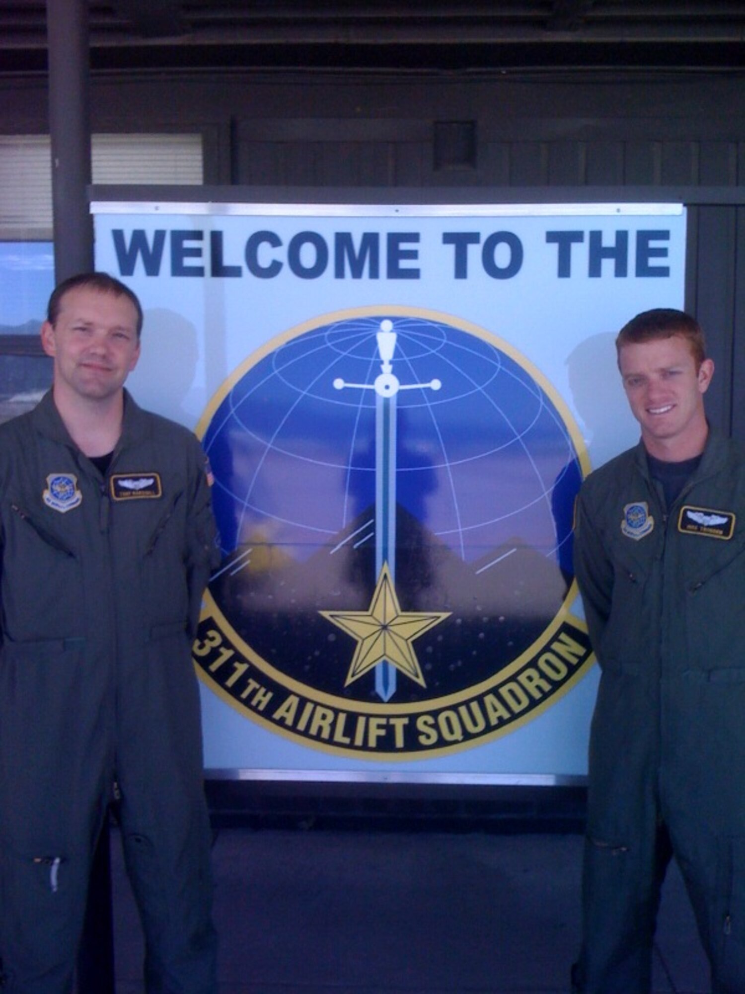 Peterson Air Force Base, Colo. -- Capts. Tony Marshall and Mike Trodden stand in front of the 311th Airlift Squadron sign before departing for Rodeo 2009. (Courtesy Photo) 