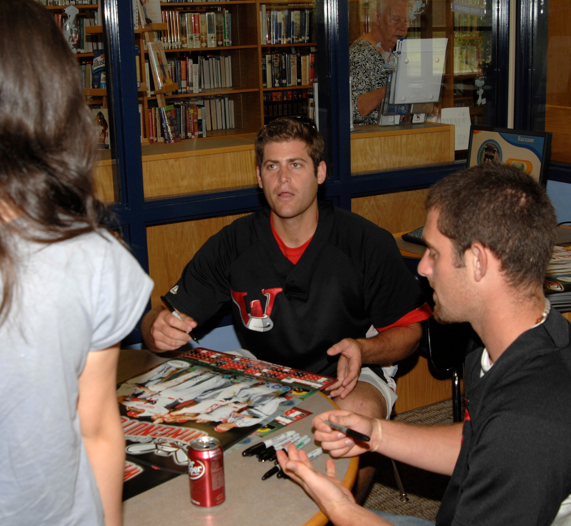 MCCONNELL AIR FORCE BASE, Kan. -- Gabby Garlow, daughter of Master Sgt. Eric Garlow, 22nd Civil Engineer Squadron, gets a poster signed by Mike Thompson and Patrick Brooks of the Wichita Wingnuts at the base library, July 14. The infielders came to sign posters for the Team McConnell members in support of the military. (Photo by Senior Airman Laura Suttles)