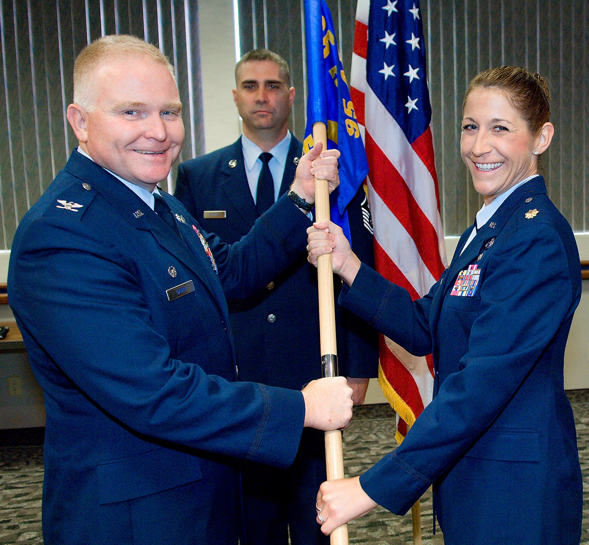 Col. Jerry Gandy, 95th Air Base Wing commander, passes Maj. Lisa Wildman the 95th Comptroller Squadron guidon, as she assumes command during a change of commmand ceremony July 10. (Air Force photo/Mike Cassidy)