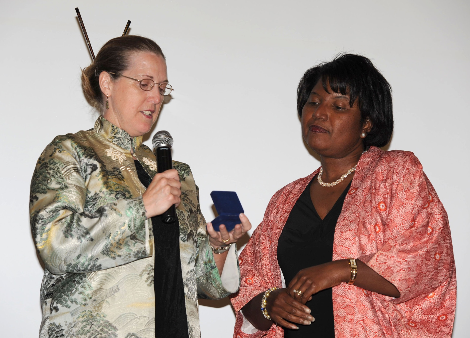 MCCONNELL AIR FORCE BASE, Kan. -- Michelle Novotny, wife of Col. Michael Novotny Maintenance Group deputy commander, presents Jeanene Dillard, wife of Col. Michael Dillard, with a military spouse’s coin for all her hard work on the base and in the local community during a farewell dinner for Colonel Dillard, July 10. (Photo by Tech. Sgt. Chyrece Campbell)