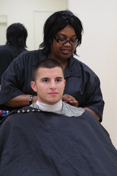 Cheryl Brown, Army & Air Force Exchange Service barber, places a neck strip on Airman 1st Class Gino Reyes, 4th Fighter Wing photographer, at the Base Exchange barber shop on Seymour Johnson Air Force Base, N.C., July 10, 2009. Neck strips are used to protect the neck from germs that may be present on a cape. (U.S. Air Force photo by Airman 1st Class Whitney S. Lambert)
