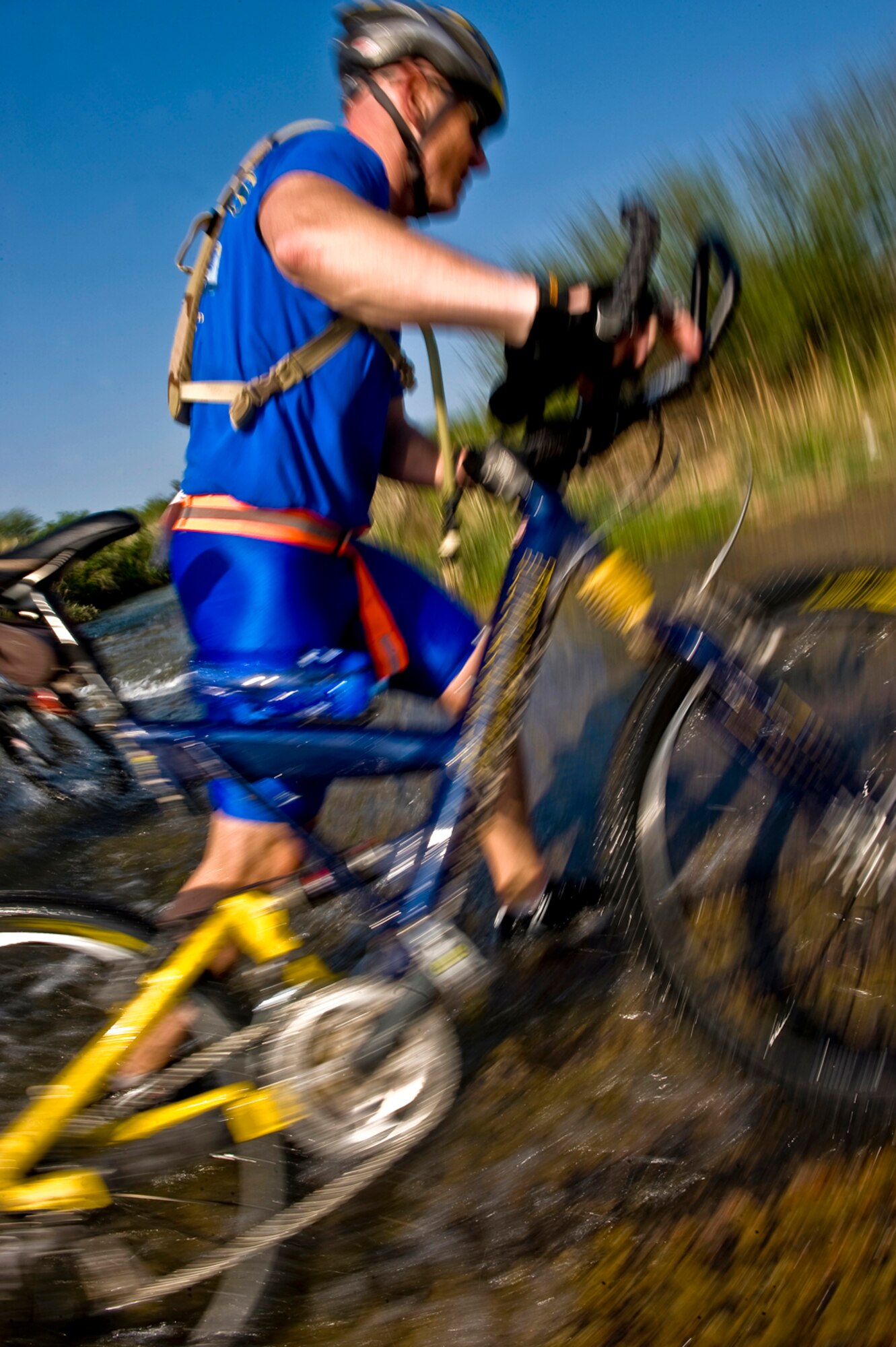 True Grit - The 35-mile course provided some tough challenges for Turnipseed and his extreme team. At left, the colonel pushes his bike through a nearly 2-foot deep creek and up a muddy embankment. (photo by Tech. Sgt. Matthew Hannen)
