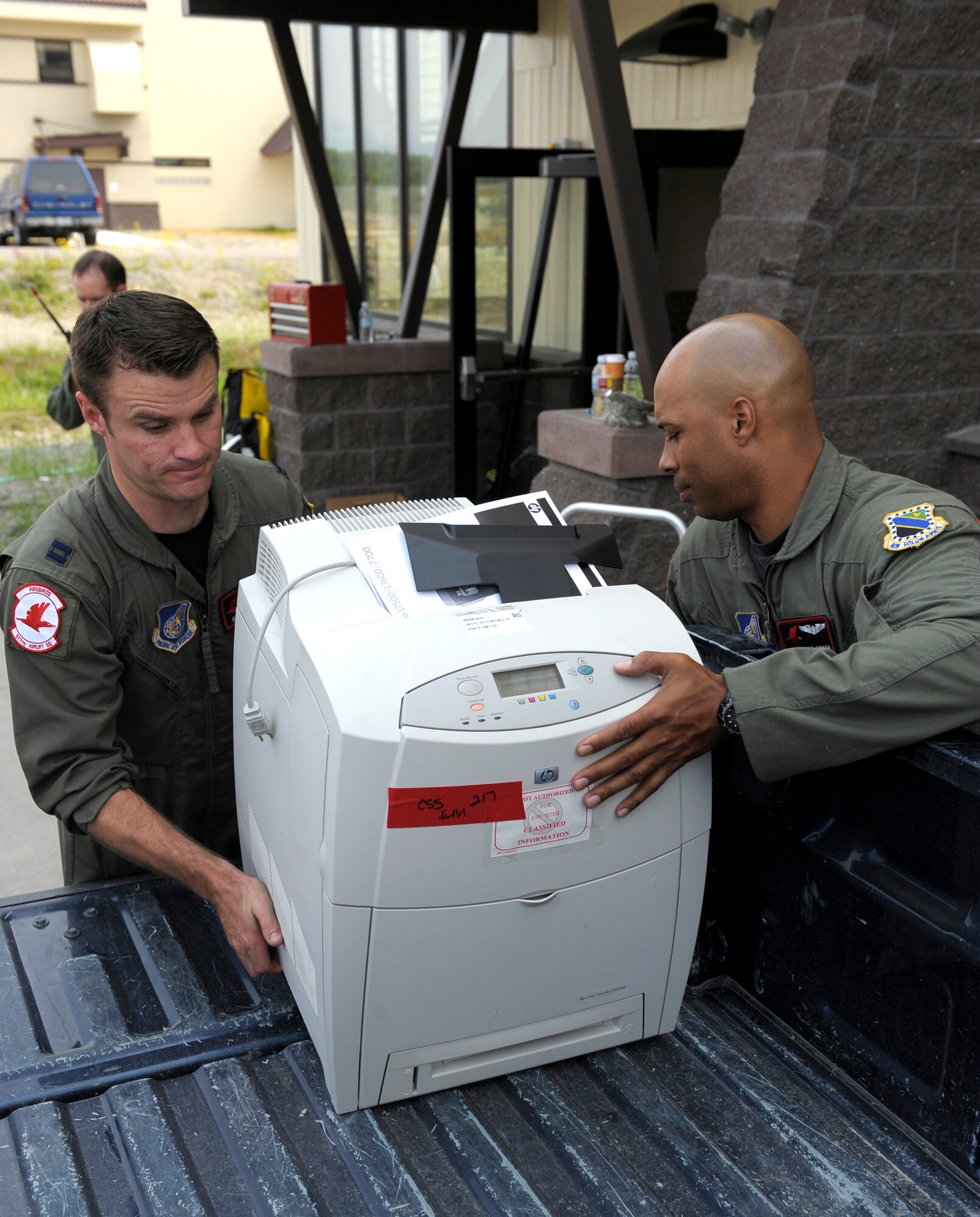 ELMENDORF AIR FORCE BASE, Alaska -- Capt. Reid Wynans and Staff Sgt. Bryan Amaya pick up a printer to carry into the 517th Airlift Squadron's new facility July 7. The squadron moved from Hangar 18 to Hangar 21. Wynans and Amaya are members of the 517th AS. (U.S. Air Force photo/Master Sgt. Keith Brown)