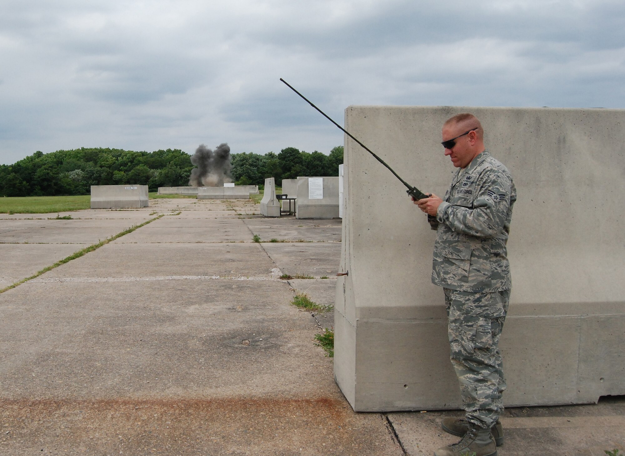 Senior Airman John Larosch, 512th Civil Engineer Squadron, detonates explosives with a transmitter July 11. CES Airmen train monthly on explosive ordnance disposal in order to stay proficient. (U.S. Air Force photo/Staff Sgt. Steve Lewis)