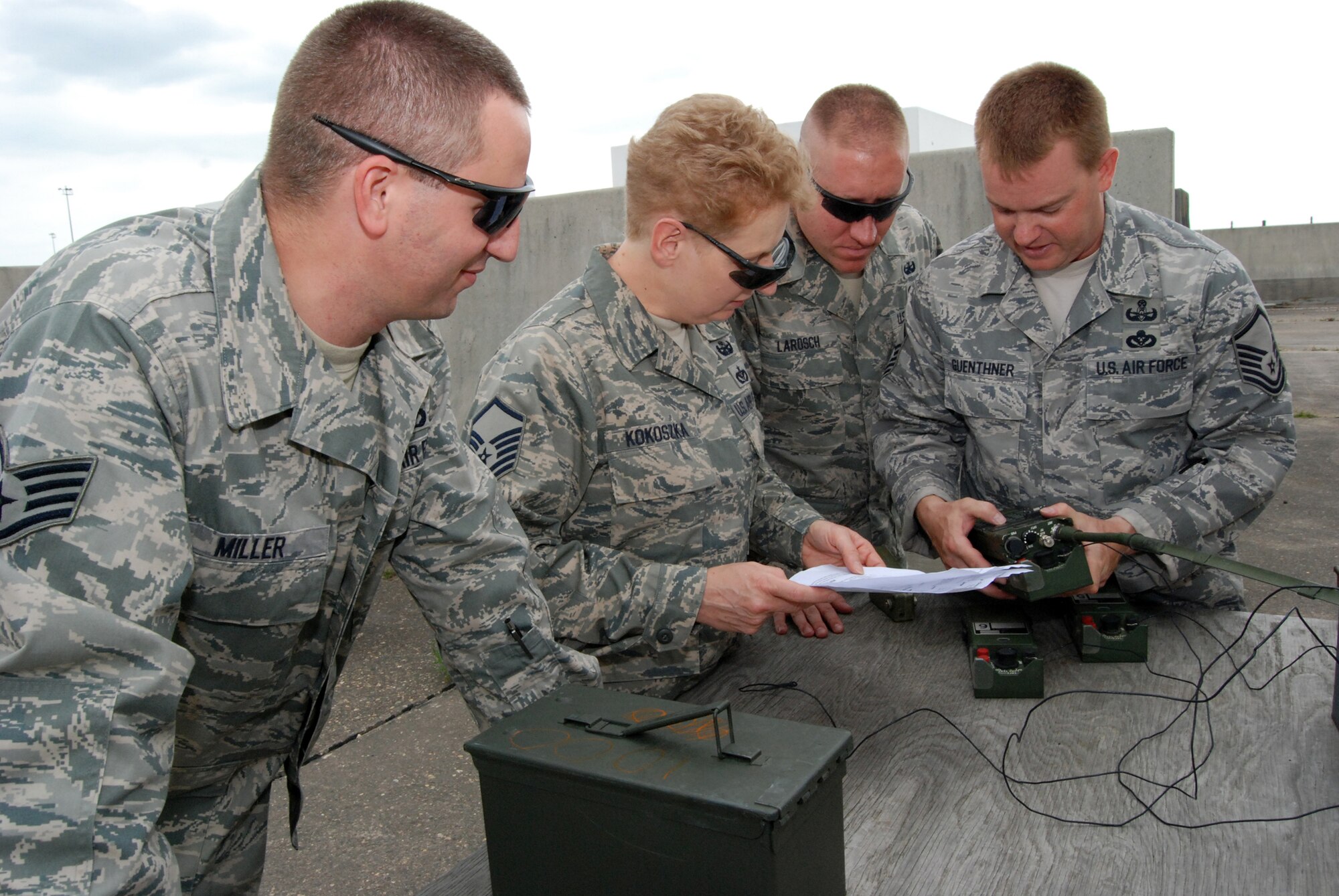 512th Civil Engineer Squadron members talk through the steps of setting up a firing device used to detonate explosives July 11. The Airmen train monthly on explosive ordnance disposal in order to stay proficient. Pictured from left to right are Staff Sgt. David Miller, Master Sgt. Mary Kokoszka, Senior Airman John Larosch and Master Sgt. Dave Guenthner. (U.S. Air Force photo/Staff Sgt. Steve Lewis)