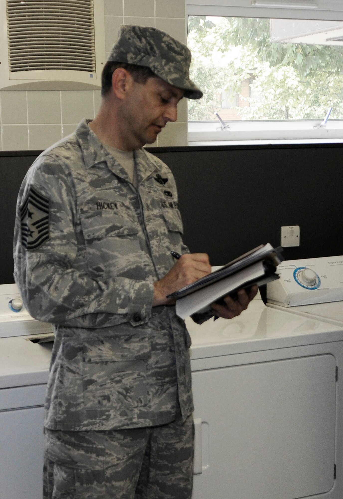 Chief Master Sgt. Antonio Hickey, the 100th Air Refueling Wing command chief, performs a dormitory inspection in the laundry room of Dorm 107 July 14. Chief Hickey and Col. Eden Murrie, 100th Air Refueling Wing commander, headed the Dorm of the Quarter competition inspection team. (U.S. Air Force photo by Senior Airman Thomas Trower)