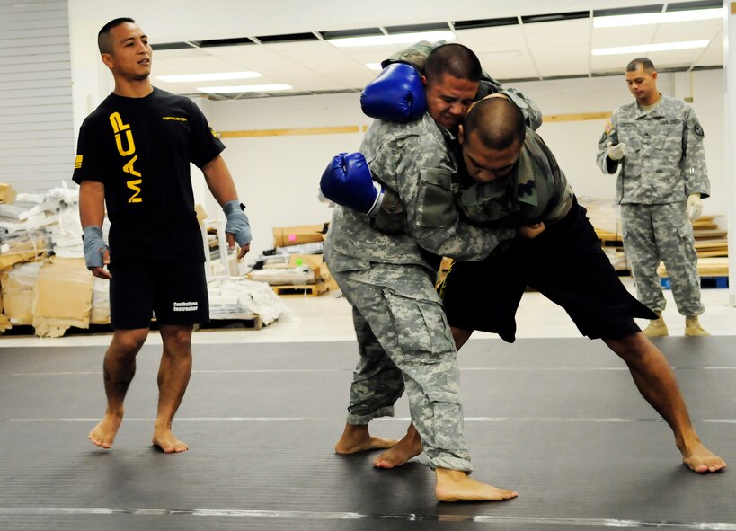 ANDERSEN AIR FORCE BASE, Guam - Lead instructor Sgt. 1st Class Duane Perez, 1st Battalion 294th Infantry Regiment, instructs the two on performing the clinch while Sgt. Josh Losongco, 1st Battalion 294th Infantry Regiment medic, keeps track of the one minute time allotted during the Modern Army Combative Training session here July 9. The program is designed to teach Soldiers and Airmen how to fight hand-to-hand when weapons use is not practical in a combat situation. (U.S. Air Force photo by Airman 1st Class Courtney Witt)