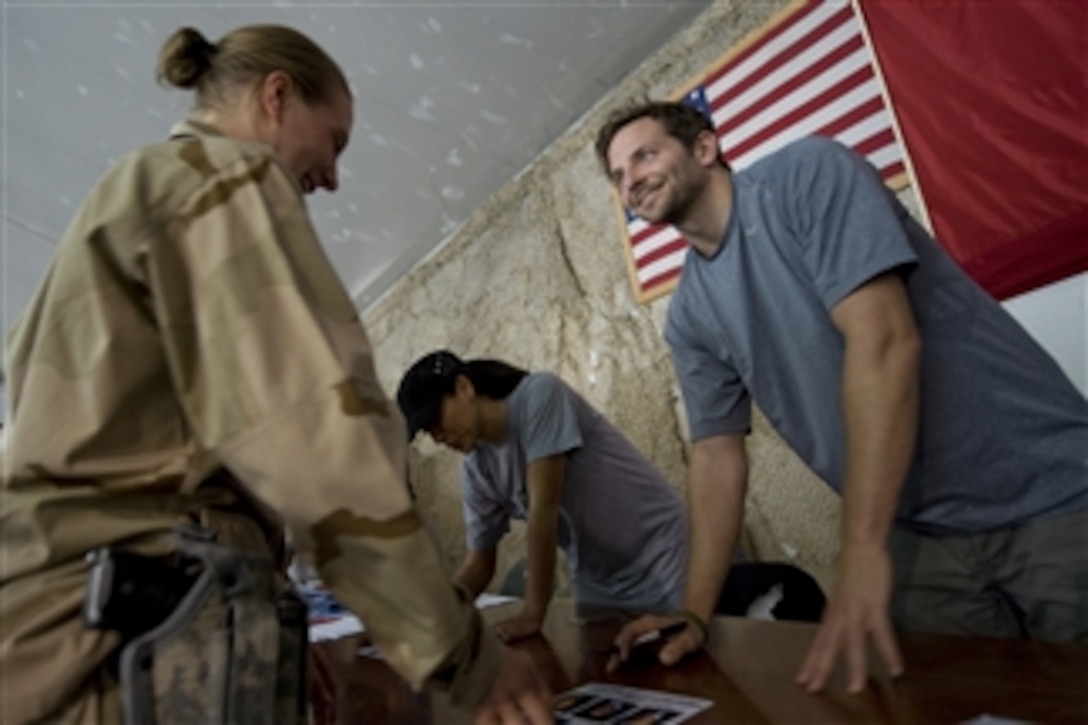Actor Bradley Cooper (right) and model Leeann Tweeden (2nd from right) sign autographs for service members at Bagram Air Base, Afghanistan, on July 14, 2009. Chairman of the Joint Chiefs of Staff Adm. Mike Mullen, U.S. Navy, is accompanying a USO tour featuring Cooper, Tweeden, Hall of Fame NFL coach Don Shula, NFL running back Warrick Dunn, and actor D.B. Sweeney on a visit to the Central Command area of responsibility.  