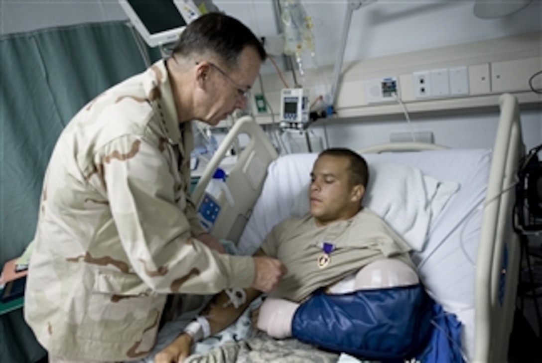 Chairman of the Joint Chiefs of Staff Adm. Mike Mullen, U.S. Navy, awards the Purple Heart to U.S Army Sgt. Marcus Love at Bagram Air Base, Afghanistan, who was wounded earlier in the day on July 14, 2009.  Love is assigned to the 3rd Brigade, 10th Mountain Division.  Mullen is accompanying a USO tour featuring Hall of Fame NFL coach Don Shula, NFL running back Warrick Dunn, actors Bradley Cooper and D.B. Sweeney and sports personality and model Leeann Tweeden on a visit to the Central Command area of responsibility.  