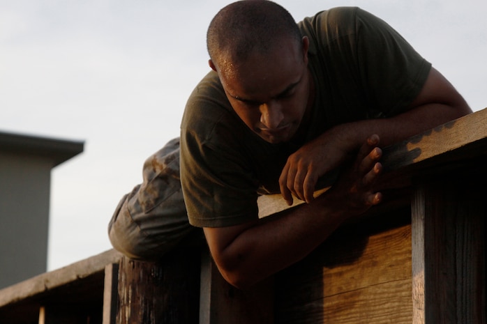 Cpl. Kevin Martin, a Headquarters and Headquarters Squadron combat marksman instructor, struggles to climb over an obstacle course wall during a competition set by Lt. Col. Tray J. Arderse, H&HS commanding officer, July 15. Ardese put forth the competition to allow career Marines the opportunity to compete for one of three seats on a C-12 slated to tour historically significant Pacific islands Aug. 5.