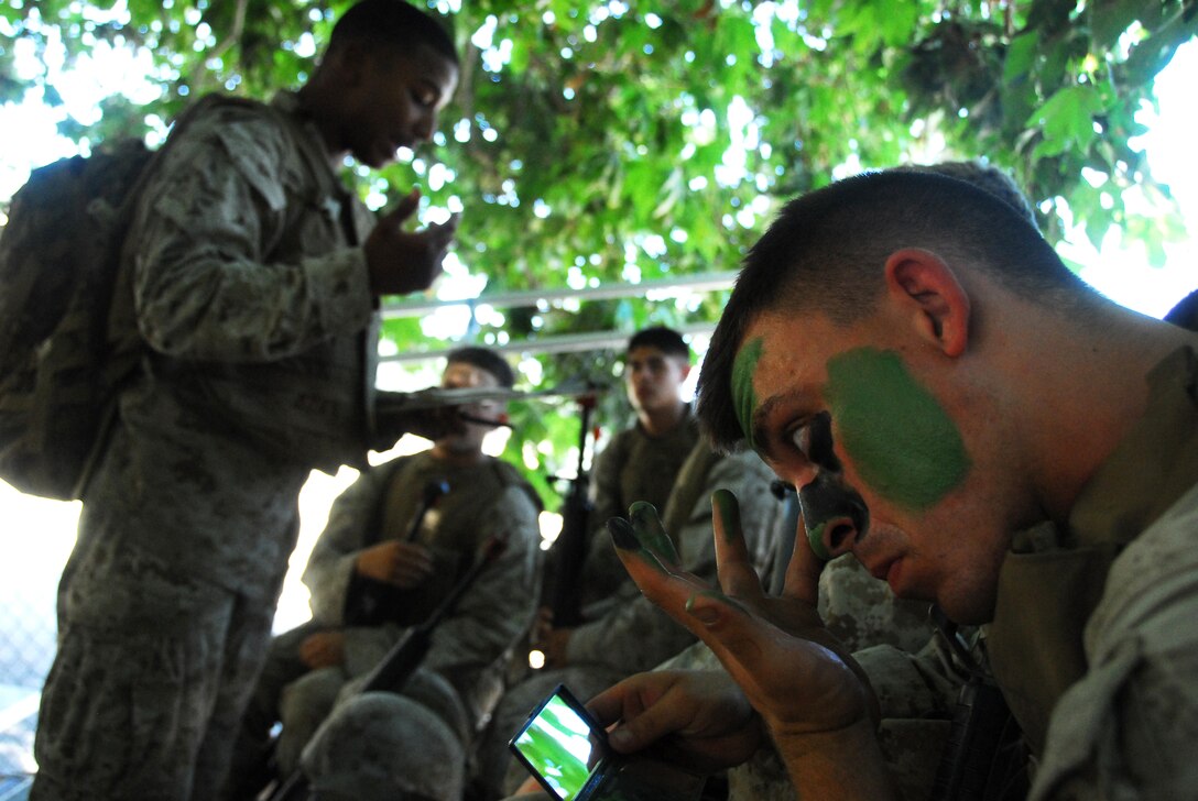 Lance Cpl. Tyler M. Peha, Yuma Headquarters and Headquarters Squadron military policeman, applies camouflage paint as Sgt. Willard Smiley, Search and Rescue quality assurance representative, briefs the squad before a patrol during the Enhanced Combat Skills course July 15, 2009, at Camp Pendleton, Calif. The Marines learned the importance of ensuring that each person involved with a mission is completely informed about every aspect from alternate routes to rally points.