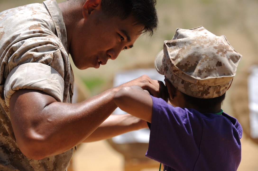 Sgt. Francisco Peralta coaches a child during archery practice at Camp Kindle West’s summer camp here July 15. Peralta and five other Marines from the 11th Marine Expeditionary Unit volunteered at the camp and brought Humvees and military equipment for the children to experience. During the day, the Marines spent time coaching archery, telling the campers about their jobs and zipping down a zip line.