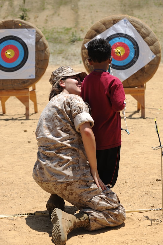 Cpl. Amber Gaskill encourages a child at Camp Kindle West’s summer camp here July 15. Six Marines with the 11th Marine Expeditionary Unit’s command element spent July 15 volunteering at the summer camp for children either infected or affected by HIV or AIDS. During the day, the Marines spent time coaching archery, telling the campers about their jobs and zipping down a zip line.