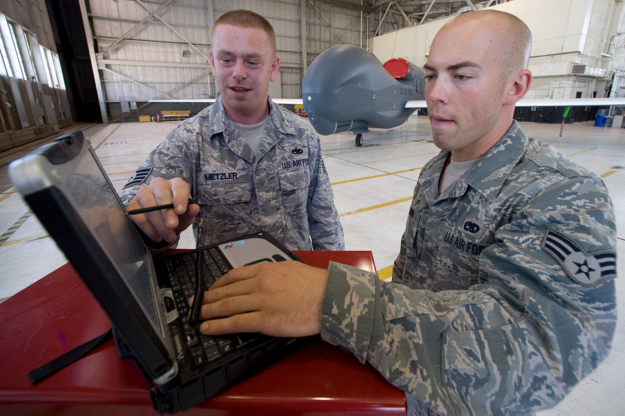 Staff Sgt. Nathaniel Metzler (left) and Senior Airman Aaron Weldon, both assigned to the 31st Test and Evaluation Squadron at Edwards Air Force Base, Calif., review a technical order for the Global Hawk aircraft. Computerized TOs provide the information required for maintenance on the aircraft and replace bulky, multi-volume books. Sergeant Metzler is a crew chief and Airman Weldon is an electrical and environmental journeyman on the Global Hawk.  (U.S. Air Force photo/Master Sgt Jack Braden)