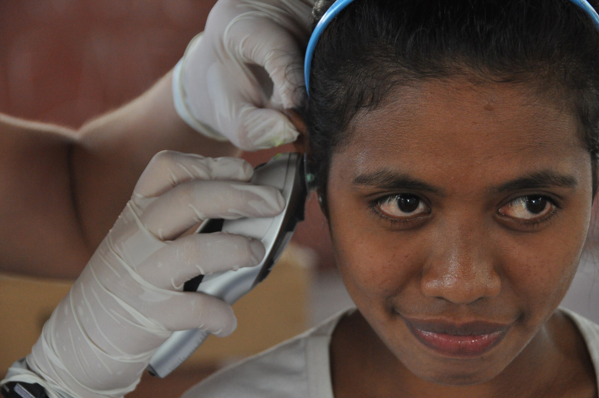 A young East Timorese woman's ear is checked by Senior Airman Ashley Cope during inprocessing at a clinic in Dili, Timor Leste, July 16.  Airman Cope is assigned to the 3rd Medical Group at Elmendorf Air Force Base, Alaska, as a labor and delivery technician. East Timorese and U.S. officials set up the clinic as part of Operation Pacific Angel 2009, a Pacific Air Forces humanitarian assistance operation led by 13th Air Force at Hickam Air Force Base, Hawaii. (U.S. Air Force photo/Tech. Sgt. Cohen A. Young)   