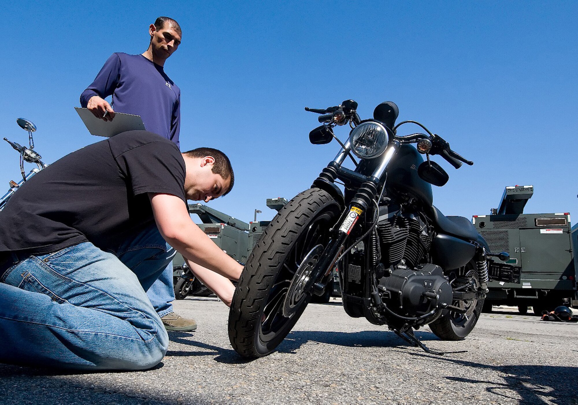 (Standing) Staff Sgt. Jared Flores and Senior Airman Christopher Dellis, 436th Aircraft Maintenance Squadron, check the air pressure on a tire during a motorcycle safety briefing July 9.  Roughly 30 motorcyclists from the 436th AMXS participated in the event, which included briefings, a motorcycle inspection and a group ride.  (U.S. Air Force photo/Tom Randle)  