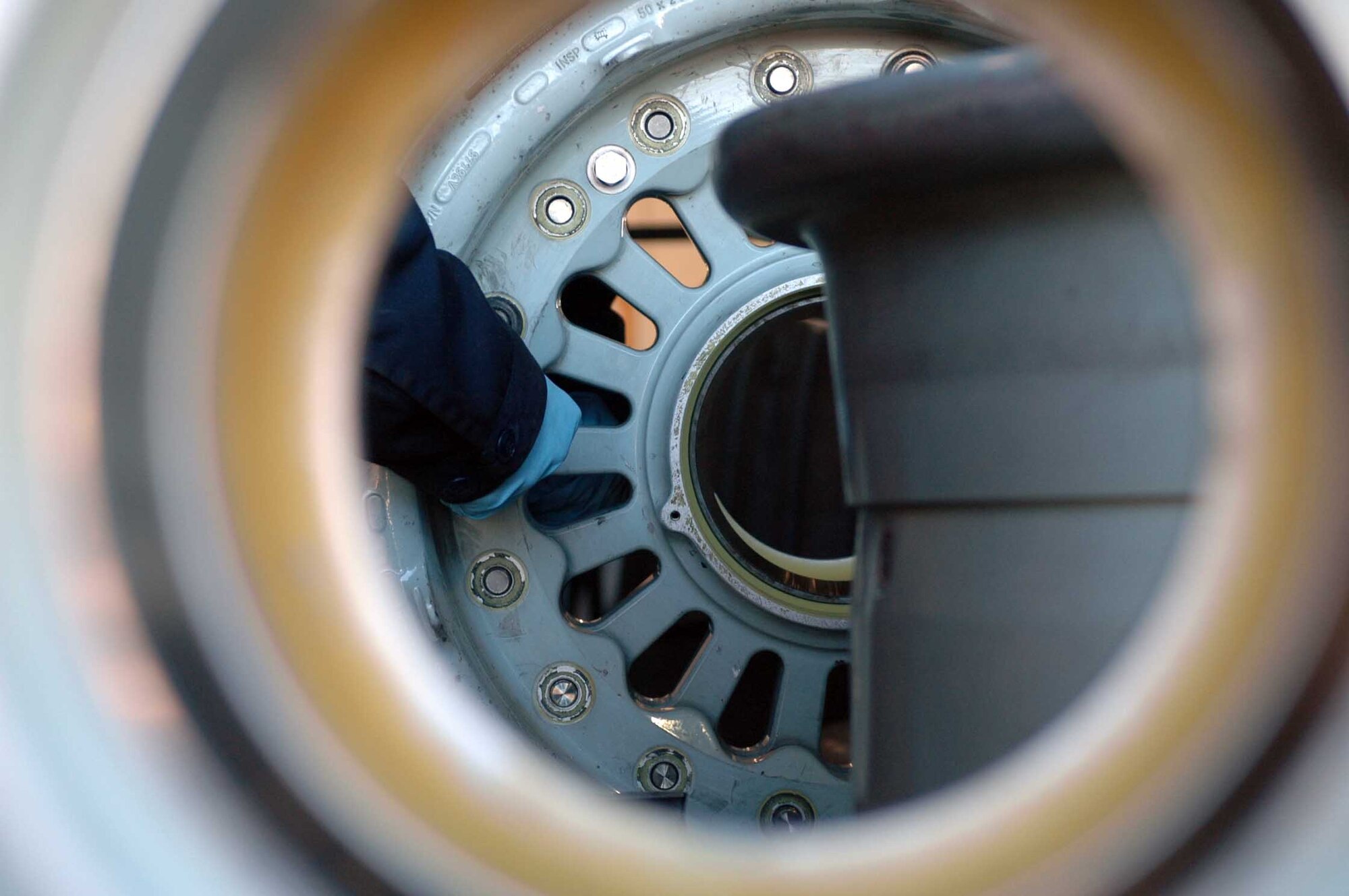 The hand of Airman 1st Class Mark Kuryn, 60th Maintenance Squadron, is seen tightening bolts to reassmble the halves of a wheel. The halves are washed and cleaned before being reassmbled. (U.S. Air Force photo/Nick DeCicco)
