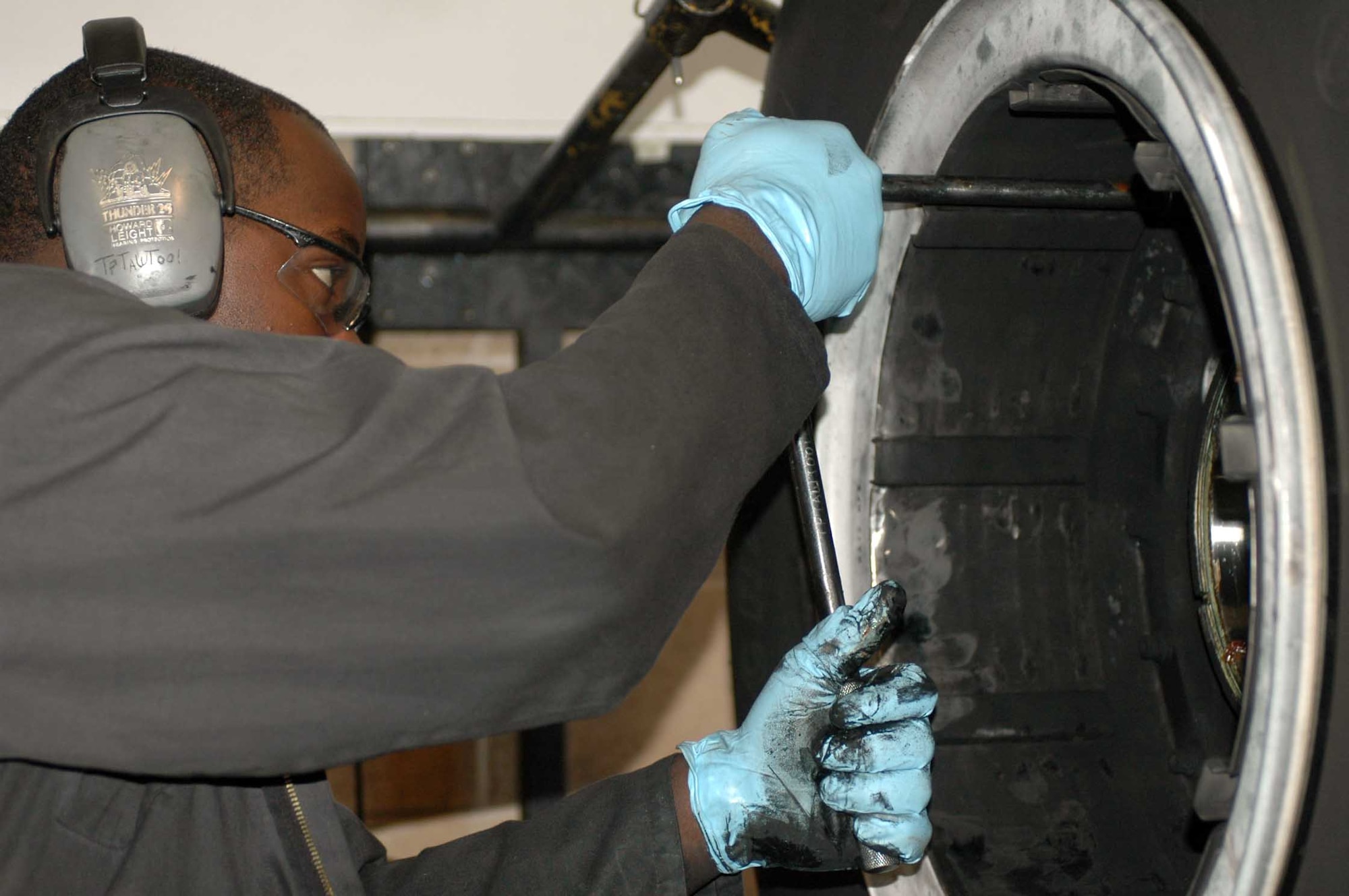 Senior Airman Maurice Gardiner holds bolts in place as members of the 60th Maintenance Squadron's Wheel and Tire Shop disassemble a wheel brought in from the flight line. The metal part of the tires is dissembled, washed and cleaned before a new rubber exterior is fitted on. (U.S. Air Force photo/Nick DeCicco)