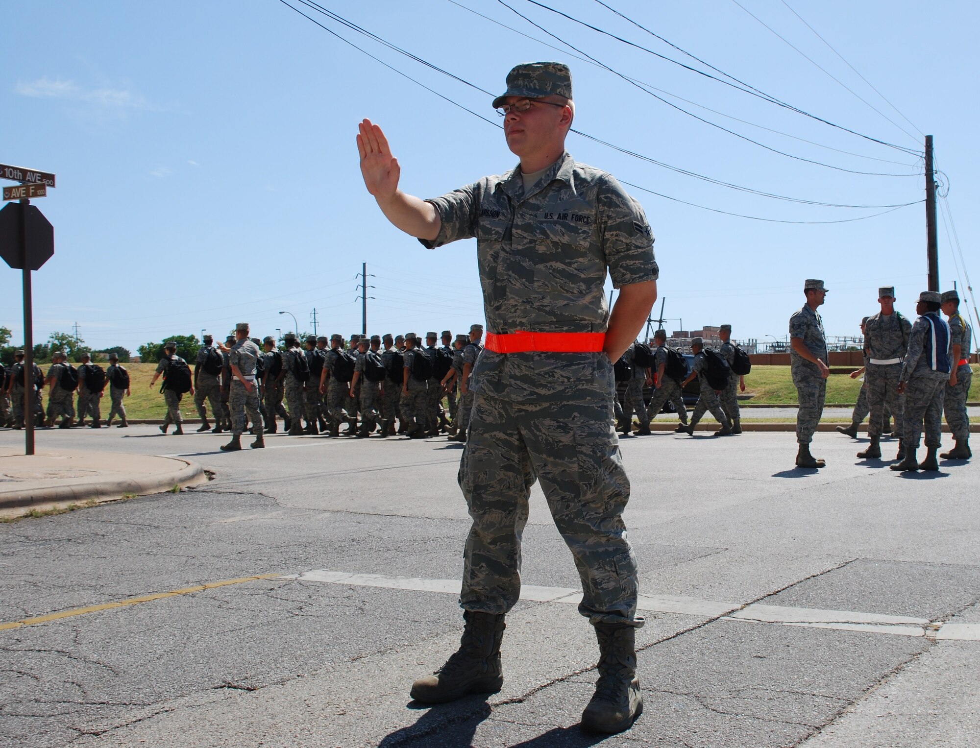 Airman 1st Class Trevor Larson, a student in the Crew Chief Heavy Flight C-130 course, stops traffic with other road guards ensuring the safety of other Airmen as the flight crosses the intersection July 15. When Airmen march in formation and cross intersections road guards halt traffic as the other troops cross the road. (U.S. Air Force Photo/ Airman 1st Class Adawn Kelsey)
