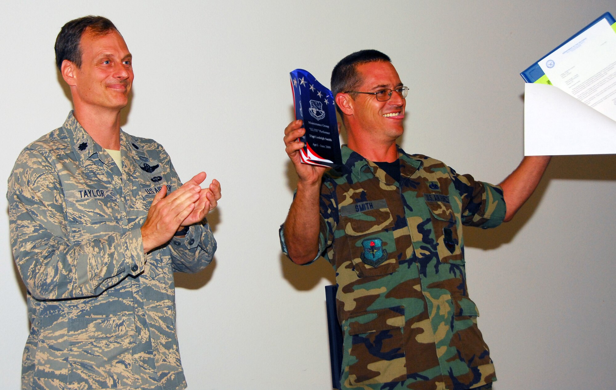 Tech. Sgt. Lesleigh Smith, the 162nd Maintenance Group’s first-ever “Elite Performer,” shows his award to his co-workers while Lt. Col. James Taylor, the group commander, applauds the achievement. Smith was picked by Colonel Taylor to receive the award from a field of six “Top Performers” recognized at the event. The plaque awarded was designed by Staff Sgt. Veronica Norzagaray of the maintenance quality assurance office. (Air National Guard photo by Master Sgt. Dave Neve)