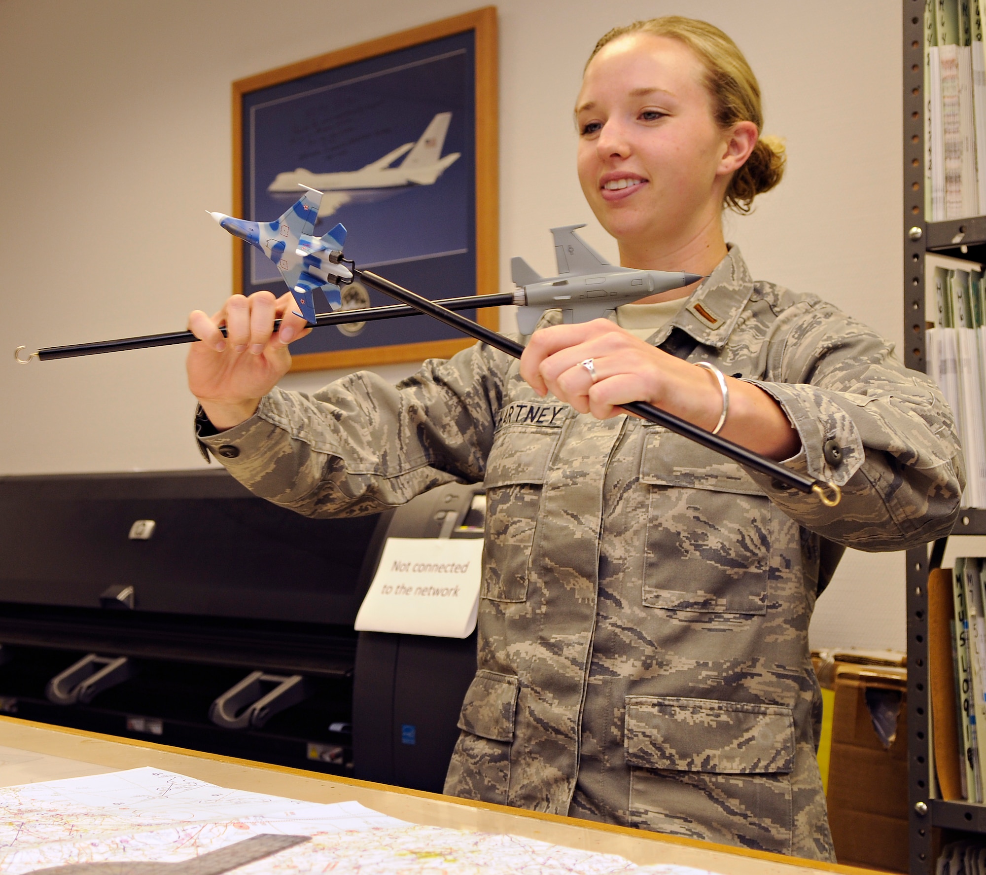 SPANGDAHLEM AIR BASE, Germany – 2nd Lt. Maureen Hartney, 52nd Operations Support Squadron officer in charge of intelligence standards and evaluations, demonstrates air-to-air tactics using aircraft models in the intelligence flight of Spangdahlem Air Base’s 52nd OSS July 14. Intel Airmen conduct training on air-to-air, surface-to–air and ground threats. (U.S. Air Force photo by Senior Airman Benjamin Wilson)