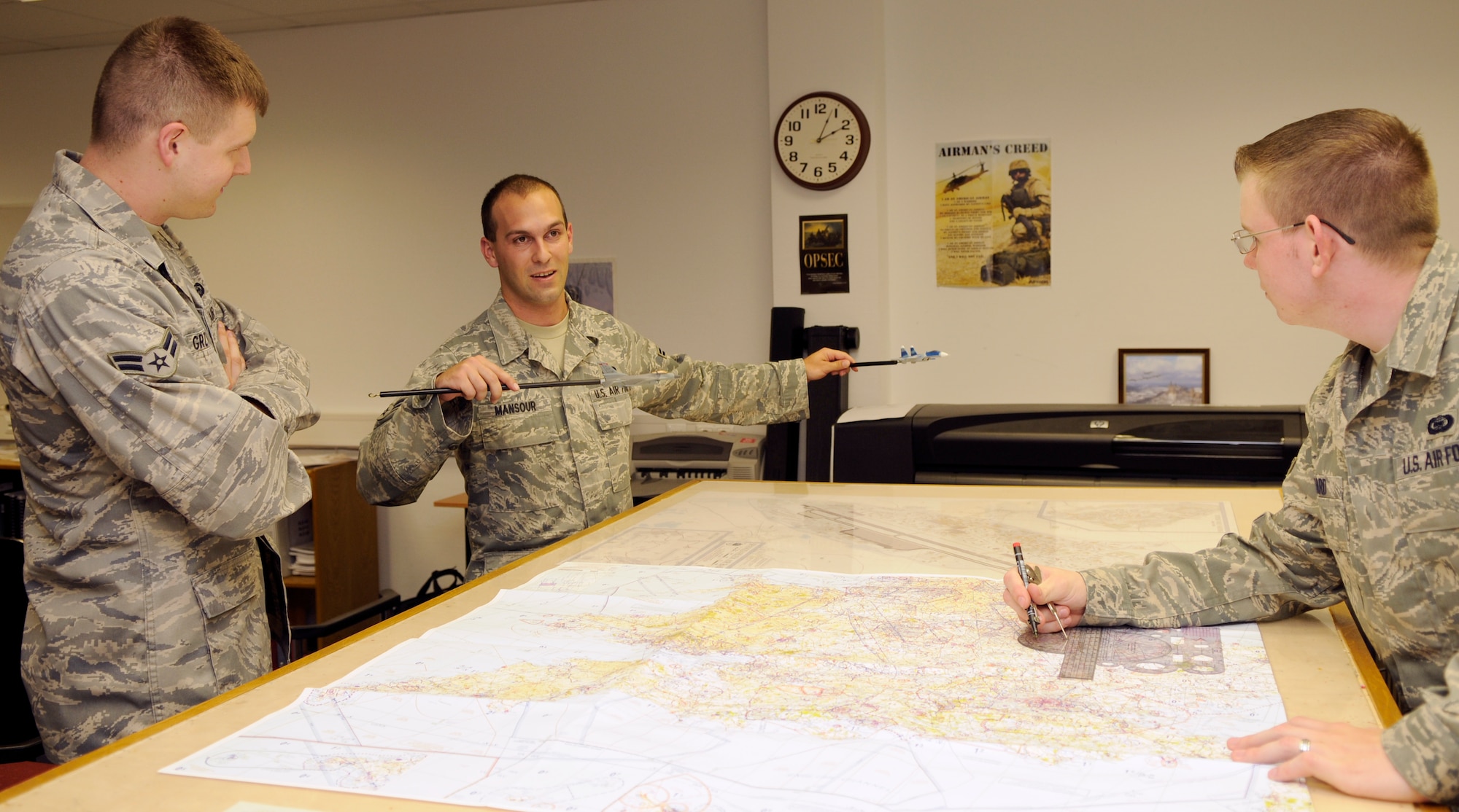 SPANGDAHLEM AIR BASE, Germany – Airman 1st Class Nicholas Mansour, 52nd Operations Support Squadron targeteer, demonstrates air-to-air tactics to his coworkers using aircraft models in the intelligence flight of Spangdahlem Air Base’s 52nd OSS July 14. Intel Airmen conduct training on air-to-air, surface-to–air and ground threats. (U.S. Air Force photo by Senior Airman Benjamin Wilson)