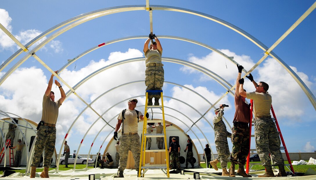 ANDERSEN AIR FORCE BASE, Guam - The 36th Medical Group and the 36th Contingency Response Group work together to construct operational tents during a simulated exercise for the Humanitarian Assistance Rapid Response Team here July 15. The HARRT is equipped to operate in an austere permissive environment during Phase III of disaster relief operations, supporting 350 to 500 patients per day and can be fully operational within six hours of arrival at the disaster site. (U.S. Air Force photo by Airman 1st Class Courtney Witt)