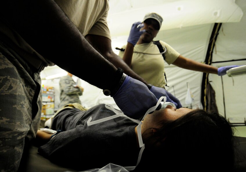 ANDERSEN AIR FORCE BASE, Guam - Medic Staff Sgt. Brandy Verette explains to patient Airman 1st Class Jeanie Snyder what the procedure will be for her condition while Medic Staff Sgt. Courtney Thompson applies a medical face mask during a simulated mass casualty exercise for the Humanitarian Assistance Rapid Response Team here July 15. The primary mission of the HARRT package is to augment and assist host nation disaster medical relief efforts with U.S. military,nongovermental organizations, and other United States Agencies for International Development and Department of Defense approved healthcare workers, and to provide organic healthcare to U.S. military personnel on the ground. (U.S. Air Force photo by Airman 1st Class Courtney Witt)