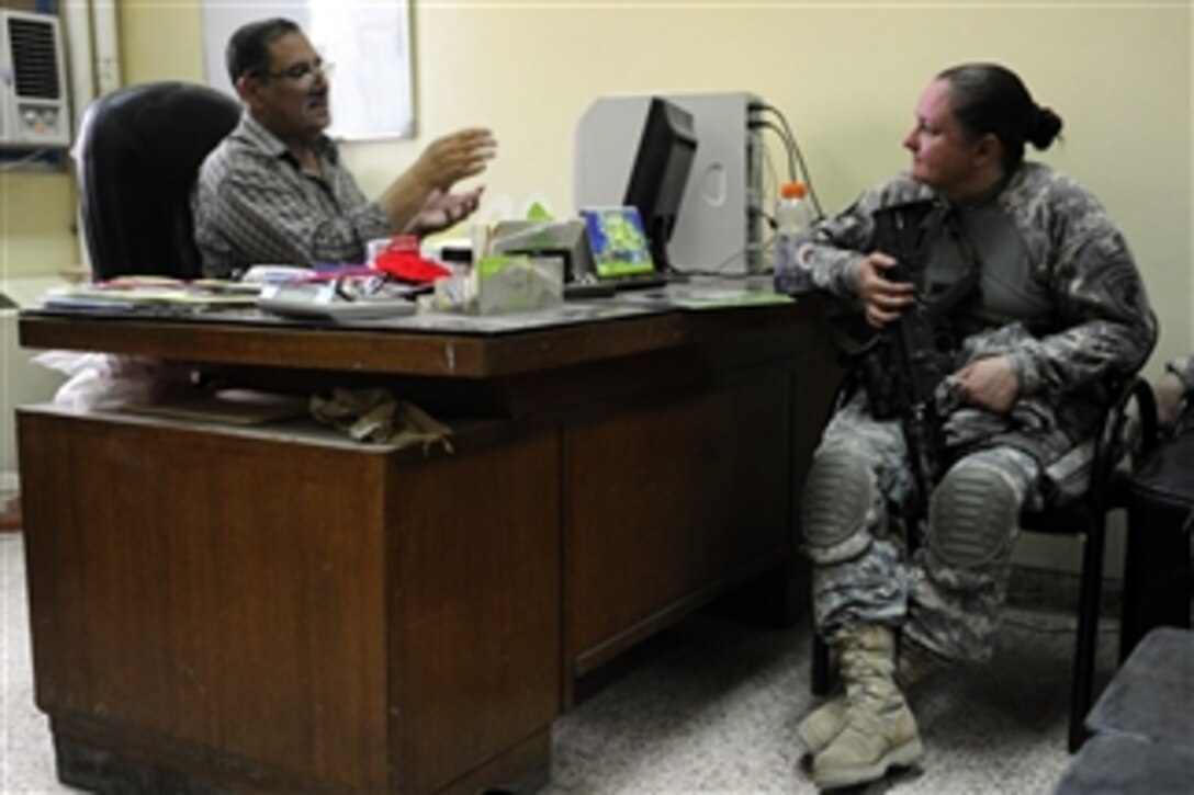 U.S. Army Sgt. Sue Sippel, from the public diplomacy office of the Salah ad Din provincial reconstruction team, speaks to Mujamma Youth Center Director Zuhair Raajb Al-Kilidaar during a site assessment and visit to hand out school supplies to children in Mujamma, Iraq, on July 9, 2009.  