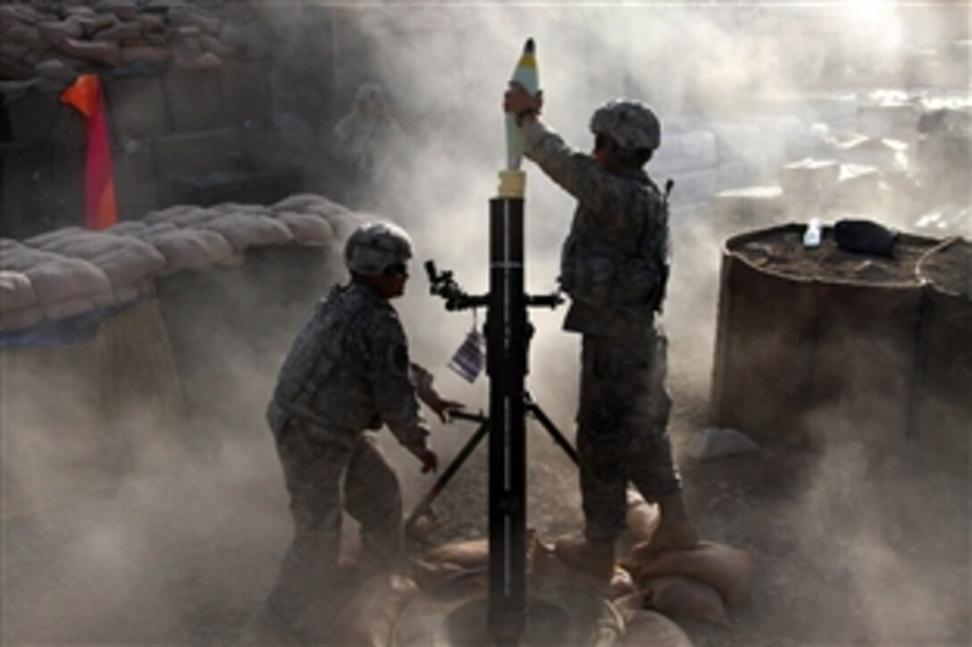 U.S. Army Spc. Gareth Warner drops a 120mm mortar round into the tube while Spc. Ricky Olivo keeps the gun on target during a fire mission on Combat Outpost Zurok in Paktika province, Afghanistan, July 13, 2009. The soldiers are assigned to the 25th Infantry Division's 3rd Battalion, 509th Airborne Infantry Regiment, 4th Brigade Combat Team.