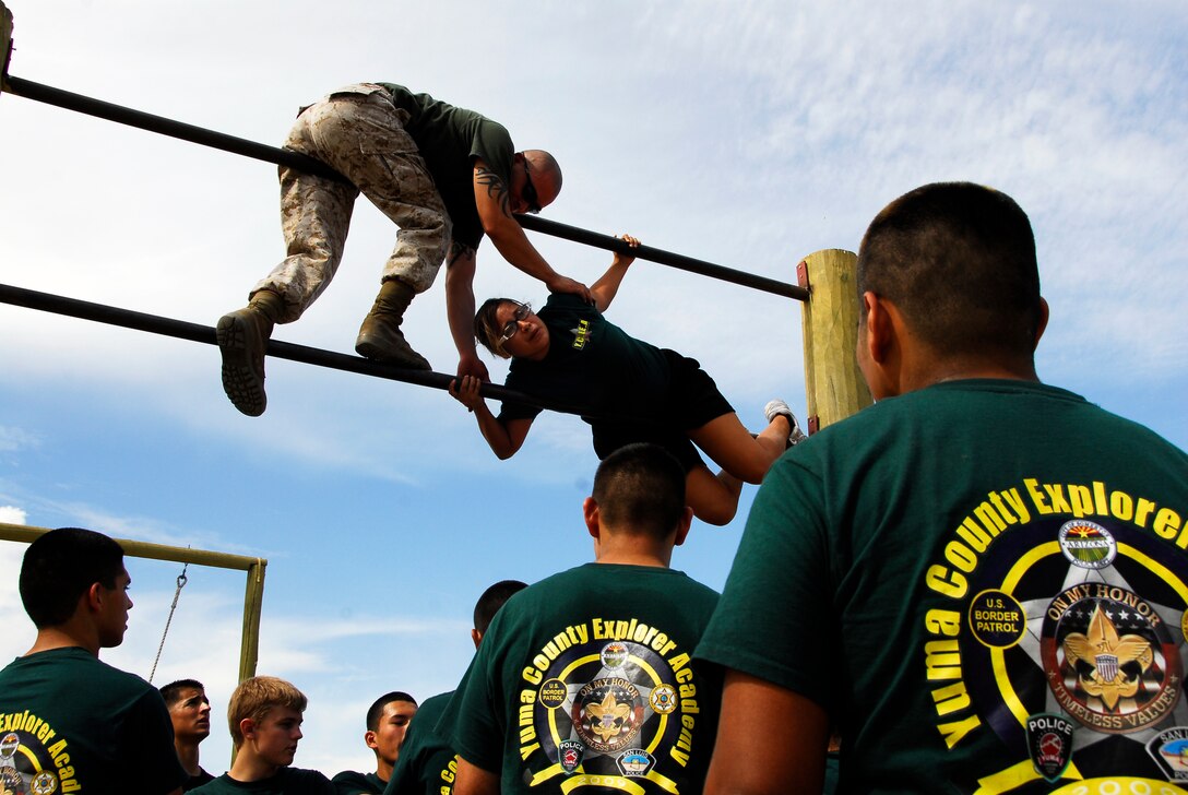Sgt. Daniel Hernandez, a Marine Corps Martial Arts Program instructor, assists Mariah Gomez, a 16-year-old member of the Yuma County Explorer Academy, in climbing the double bars of the obstacle course at the Marine Corps Air Station in Yuma, Ariz., July 16, 2009. The YCEA, an organization for youth ages 14-20 with interest in one day serving in law enforcement, spent July 13-17 on station participating in a variety of activities including MCMAP training and using the indoor simulated marksmanship trainer.