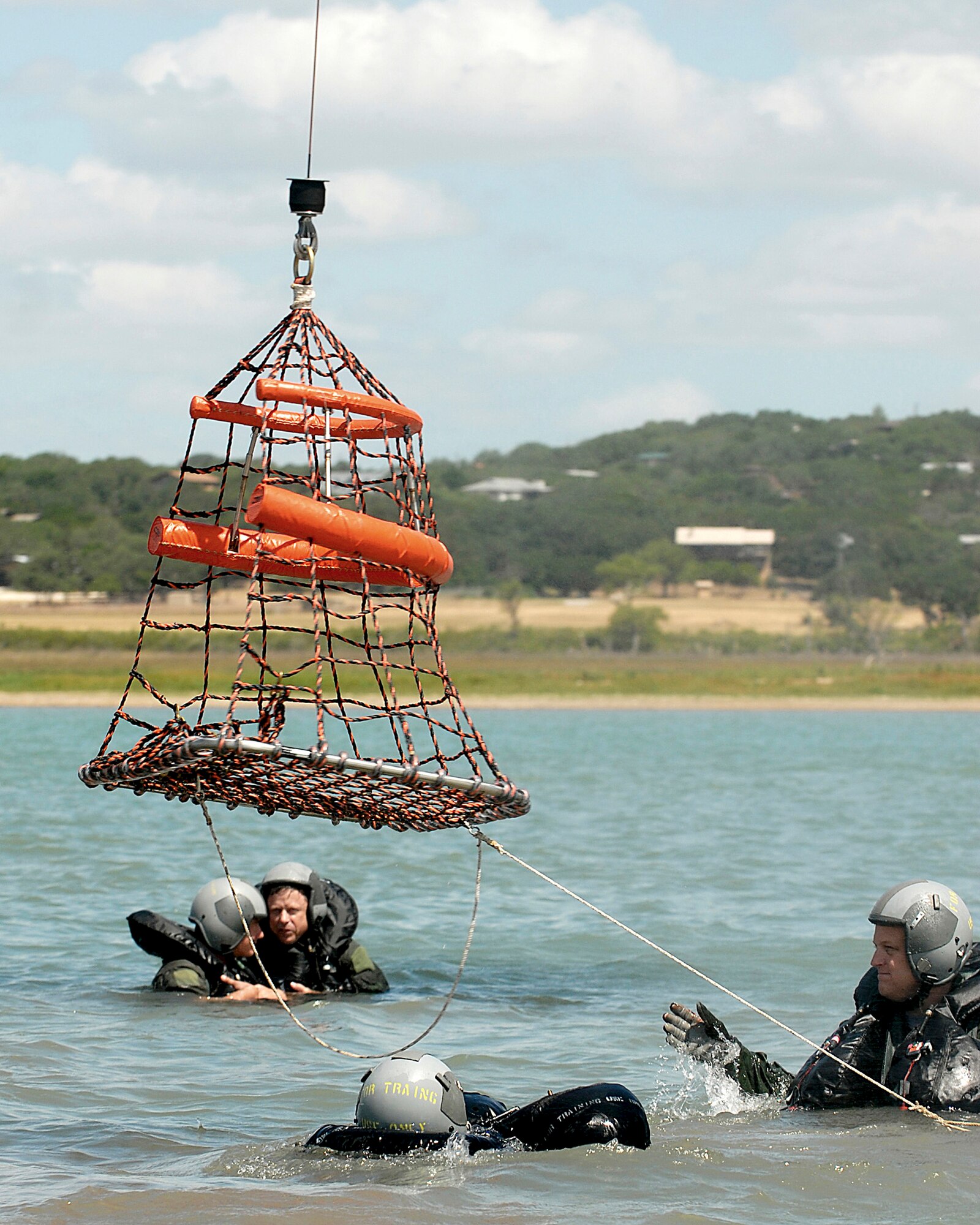 Lt. Col. Michael McCoy (right), an F-16 Fighting Falcon pilot, guides an aerial rescue basket to others participating in water survival training July 11 at Canyon Lake, Texas.  He is assigned to the Texas Air National Guard's 149th Fighter Wing at Lackland Air Force Base, Texas. (U.S. Air Force photo/Master Sgt. Robert Shelley) 
