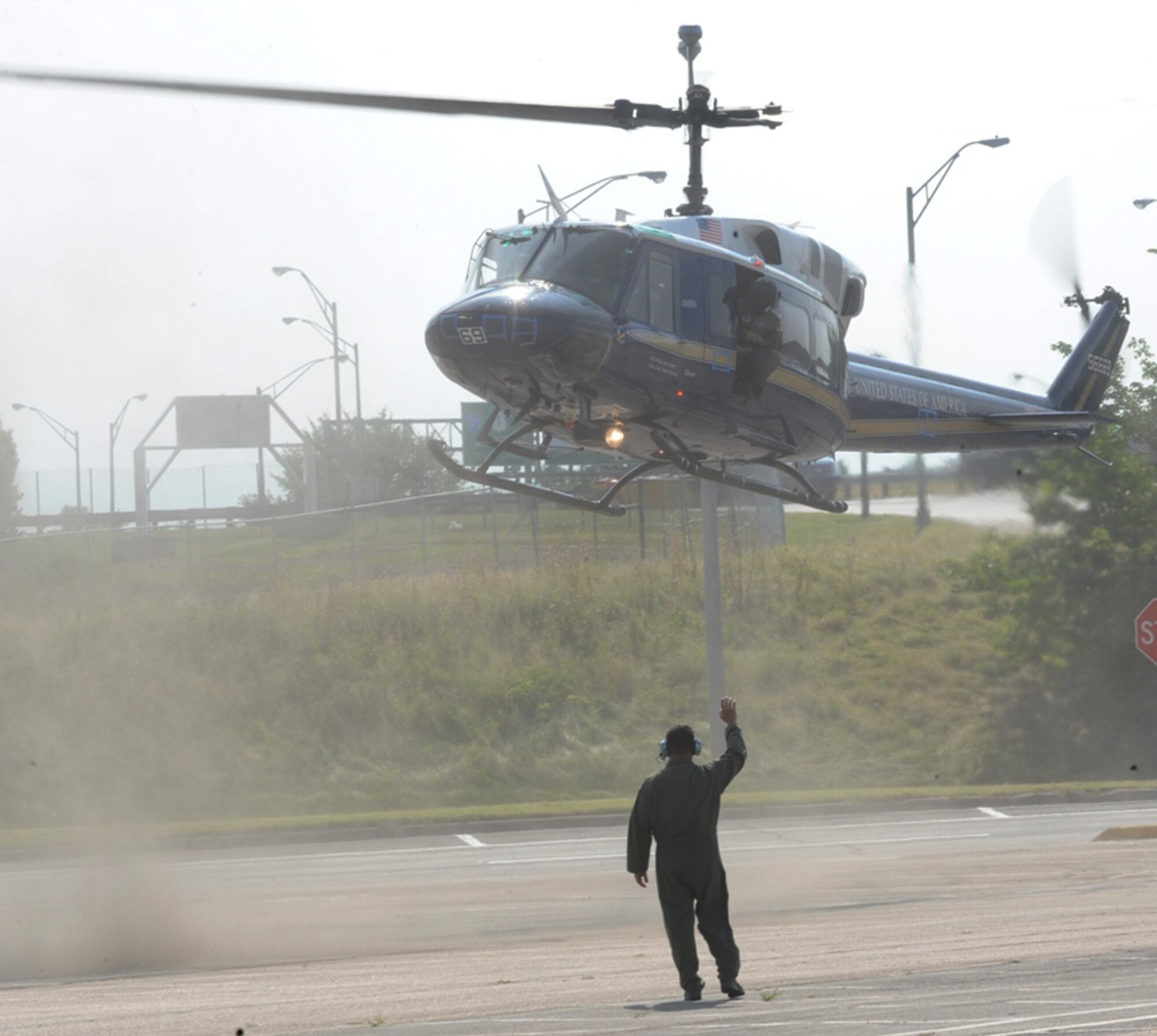 Capt. Daniel Ramirez flags a clean helicopter into the "landing zone" that was a vacant Pentagon parking lot that had been coated in a simulated biological agent July 11 at the Pentagon. The clean helicopter and its pilots were later swabbed to measure how contaminated they became as a result of the rotor wash. Air Force District of Washington Airmen worked with 18 different state and federal agencies assisting the Pentagon Force Protection Agency in an Operational Response Test designed to provide first responders with information on the best methods to decontaminate people following a biological attack. Captain Ramirez is a pilot with the 1st Helicopter Squadron at Andrews Air Force Base, Md. (U.S. Air Force photo) 
