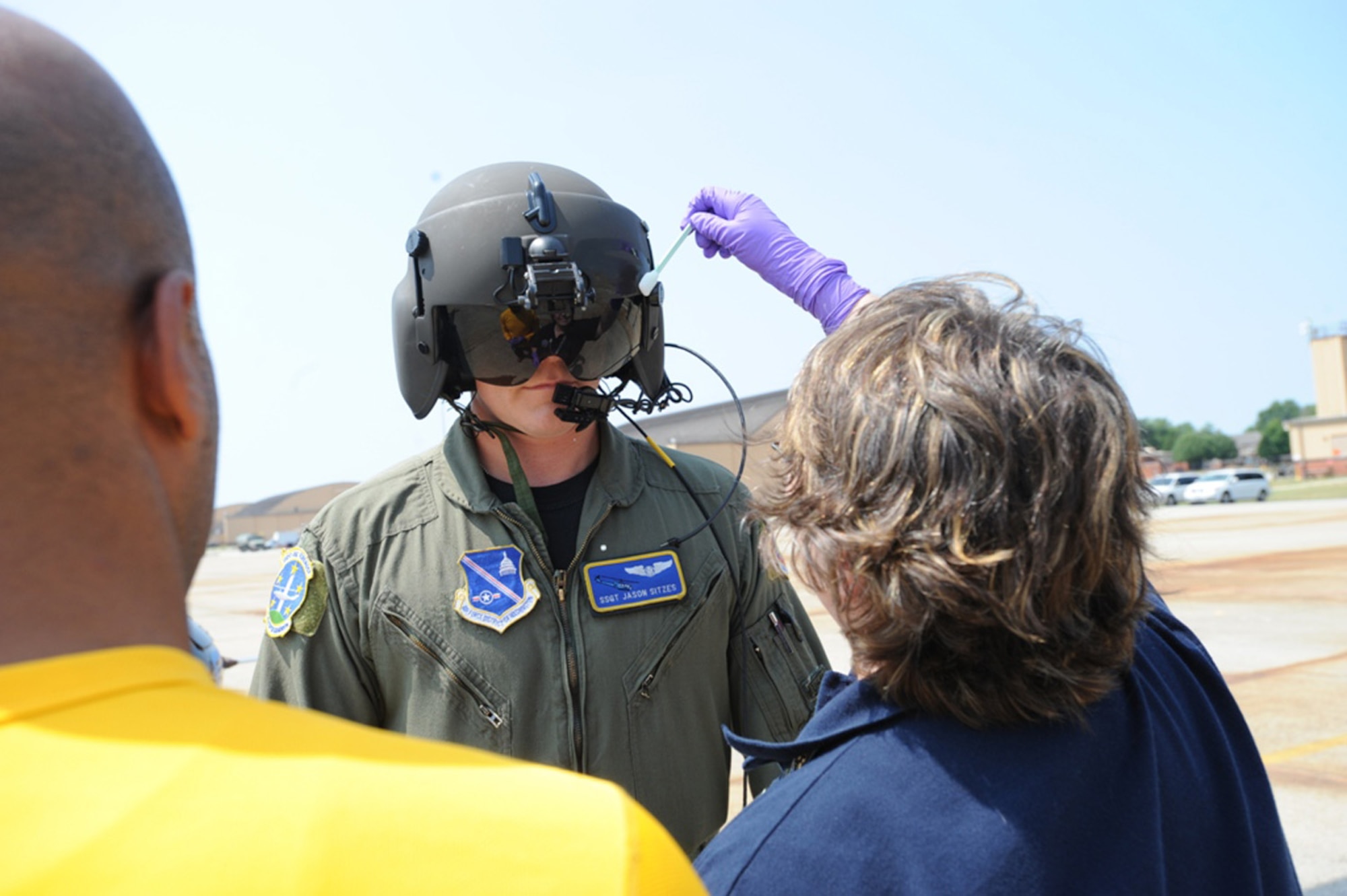Air Force District of Washington employee Debra Robinson swabs Staff Sgt. Jason Sitzles' flight helmet for bacterial contamination July 11 at the Pentagon. Sergeant Sitzles, from the 1st Helicopter Squadron on Andrews Air Force Base, Md., took part in a biological attack exercise and evacuation. Samples taken from the entire crew indicate the amount of contaminant they were exposed to during the evacuation. AFDW Airmen worked with 18 different state and federal agencies assisting the Pentagon Force Protection Agency in an Operational Response Test. The test was designed to provide first responders with information on the best methods to decontaminate people following a biological attack. (U.S. Air Force photo)