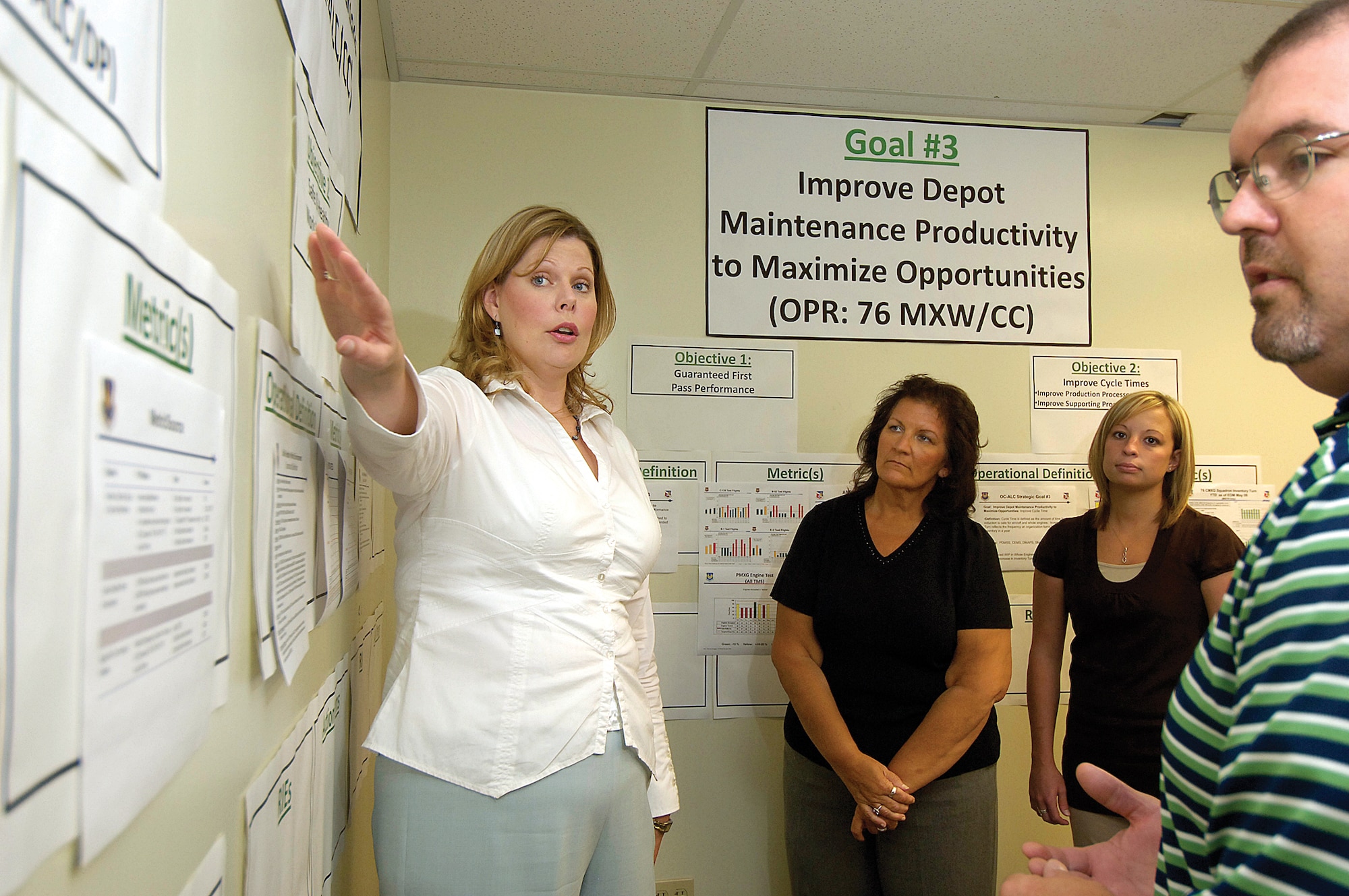 Walls lined with plans to continue streamlining Oklahoma City Air Logistics Center processes are the focus of Stacia Franks who discusses the center's strategic goals with facilitators. From left, Leigh Ann Bryson, Shelly Young and Clint Gill. (Air Force photo by Margo Wright) 
