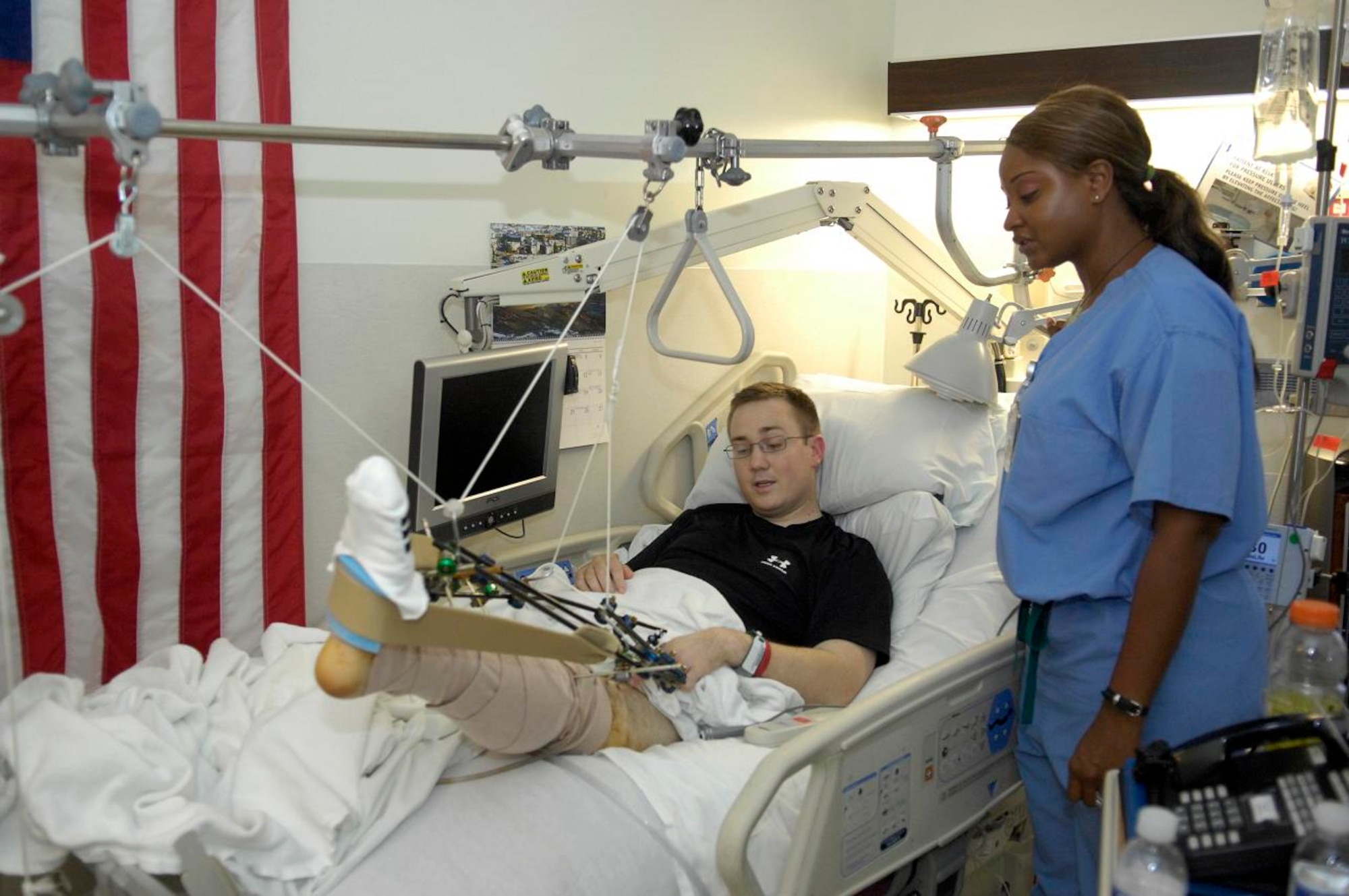 Staff Sgt. David Flowers gives his nurse, Latrice Perryman, an update on his pain levels while she takes his vital signs in his room on Ward 57 at Walter Reed Army Medical Center.   Sergeant Flowers is expected to be at Walter Reed at least a year for rehabilitation to learn to walk, drive and swing golf clubs with a prosthetic right leg. (U.S. Air Force photo by Staff Sgt. Sarah E. Stegman) (RELEASED)