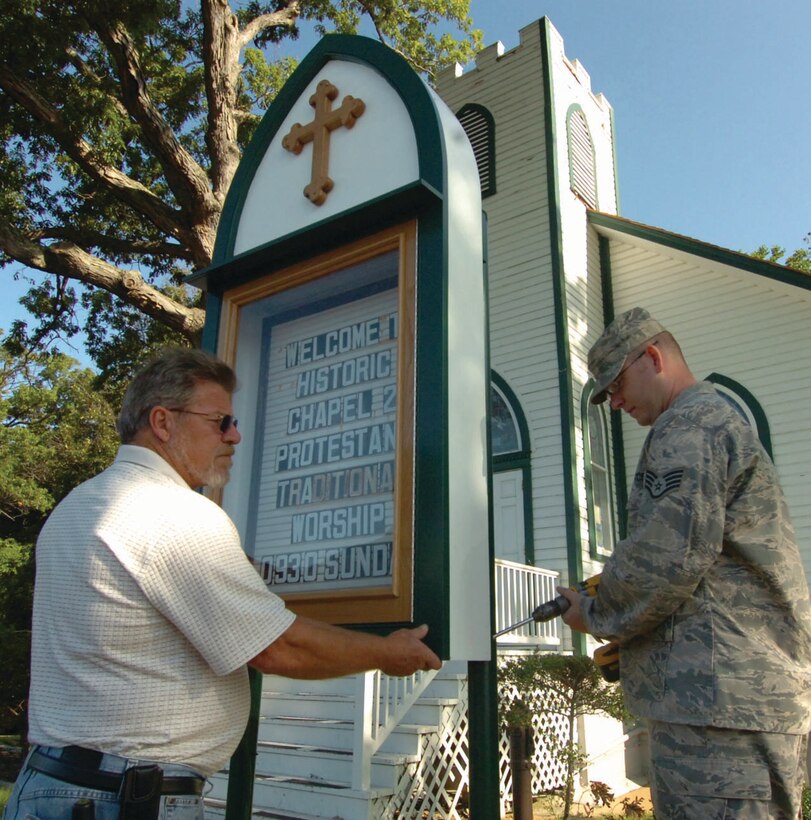 Chuck Young, 316th Civil Engineer Squadron structural shop supervisor, steadies framework of new replica of Chapel II marquee is secured by Staff Sgt. Adam Perkins, 316 CES structural craftsman on the east side of Andrews.  The renovation is just one of few upgrades being made to the historical 155-year-old church. (U.S. Air Force photo/ Bobby Jones)