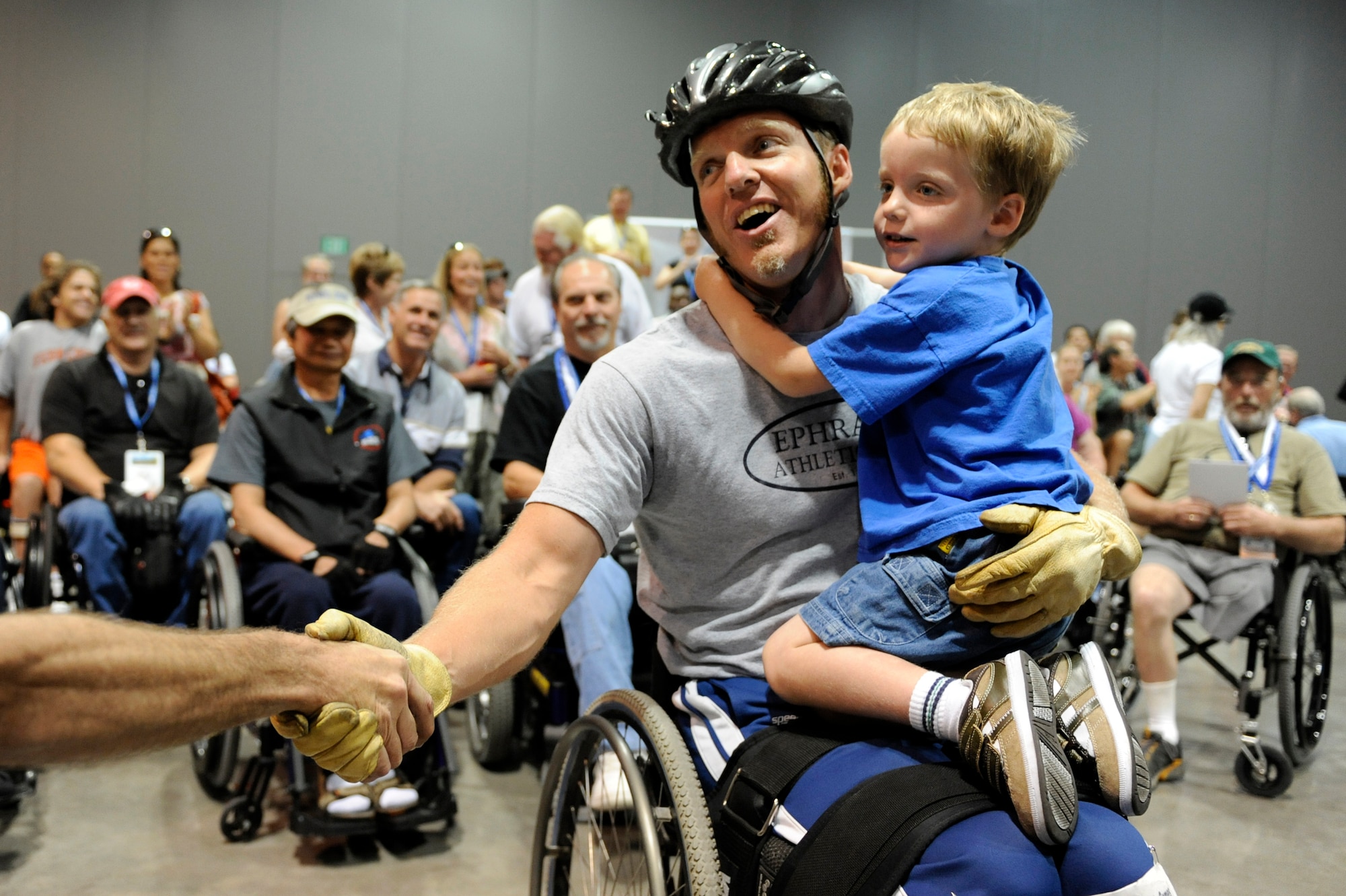 Sean Halsted shakes hands with a fan as he holds his son, Ethan, 5, after completing the slalom super G competition during the 29th National Veterans Wheelchair Games July 16 in Spokane, Wash. Mr. Halsted is an Air Force veteran and resides in Rathdrum, Idaho. (U.S. Air Force photo/Staff Sgt. Desiree N. Palacios)