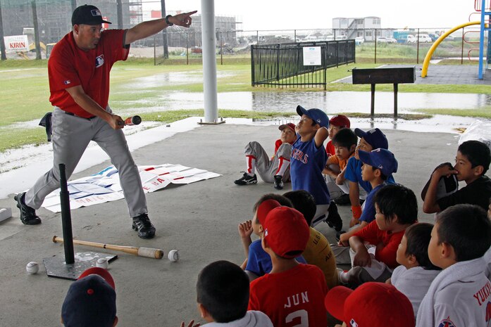 Major League Baseball Envoy Coach David Palese explains to local Japanese children the proper way to generate power with their swing during a baseball clinic at the Penny Lake Pavilion here hosted by the Boys and Girls Club Youth and Teen Center here July 17. Palese explained to the children the best way to generate power is to keep the bat close to the body and take a short quick swing at the ball.