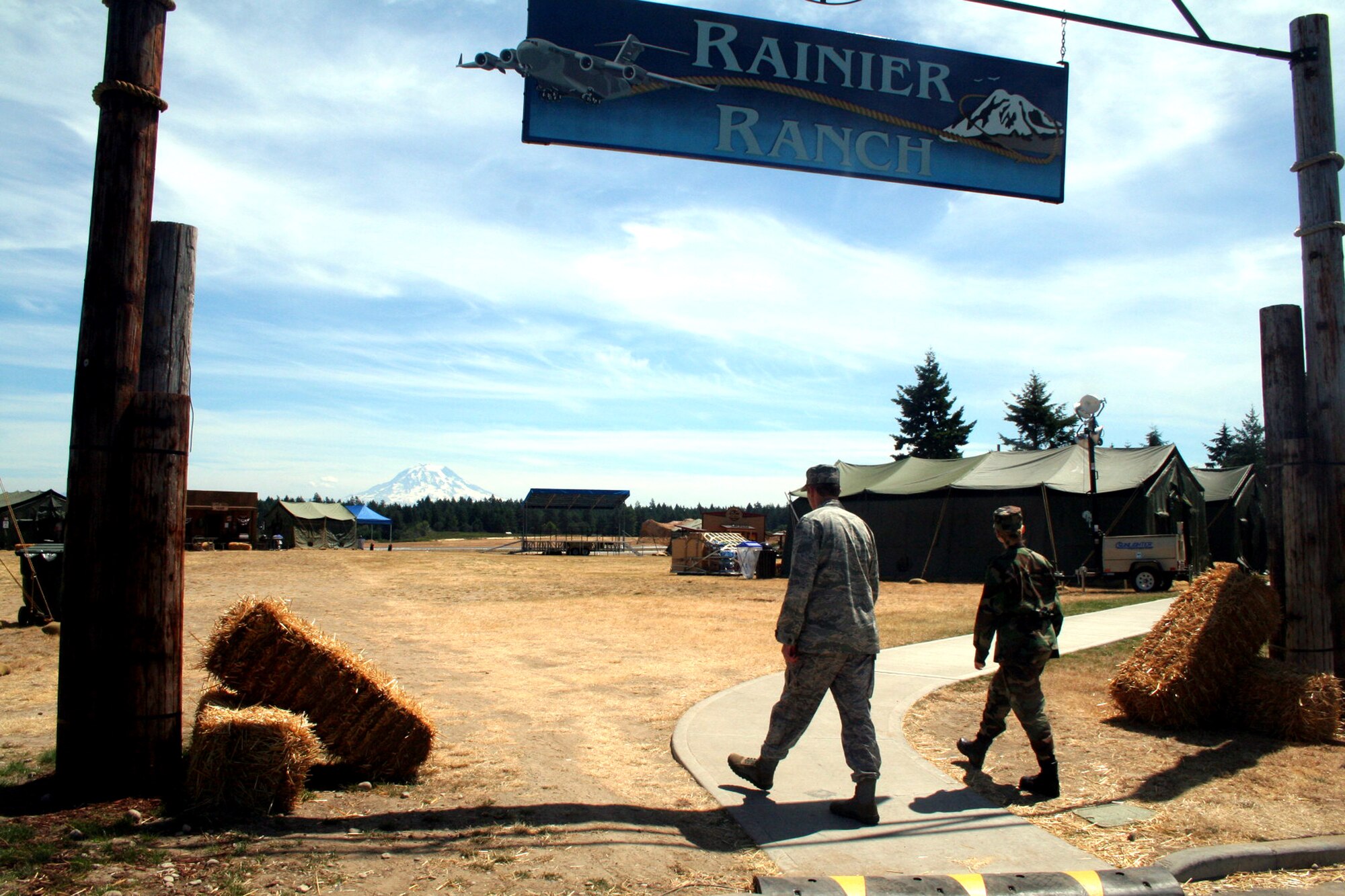 Two Airmen walk in to Rainier Ranch on McChord Air Force Base, Wash., July 18, 2009.  Rainier Ranch serves as "entertainment central" for Air Mobility Command's RODEO 2009.  The ranch is an open space holding 46 tents where some of the more than 100 teams participating in RODEO can display items from their unit, base or country.  (U.S. Air Force Photo/Tech. Sgt. Scott T. Sturkol)q